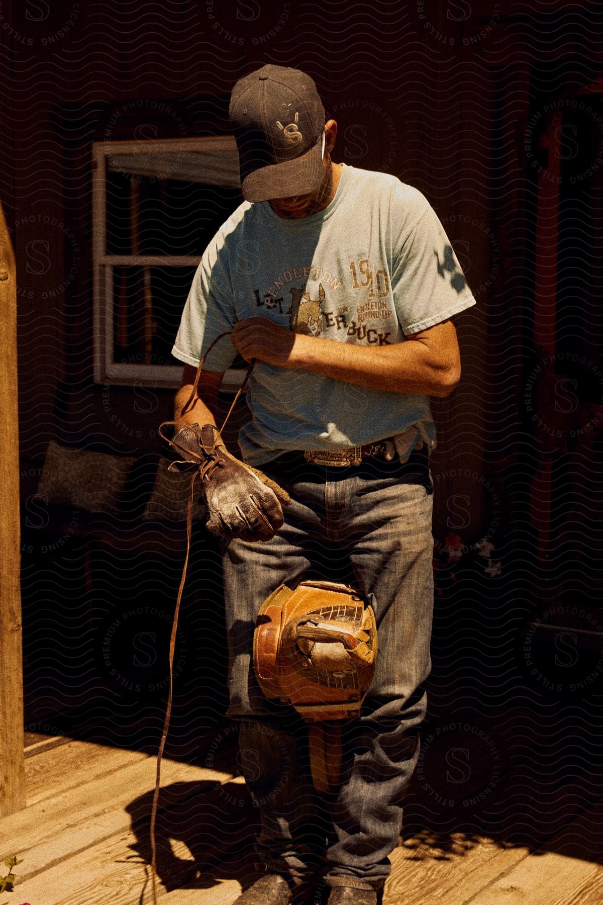 A male worker cradles a power tool between his legs while he's pulling a long cord.