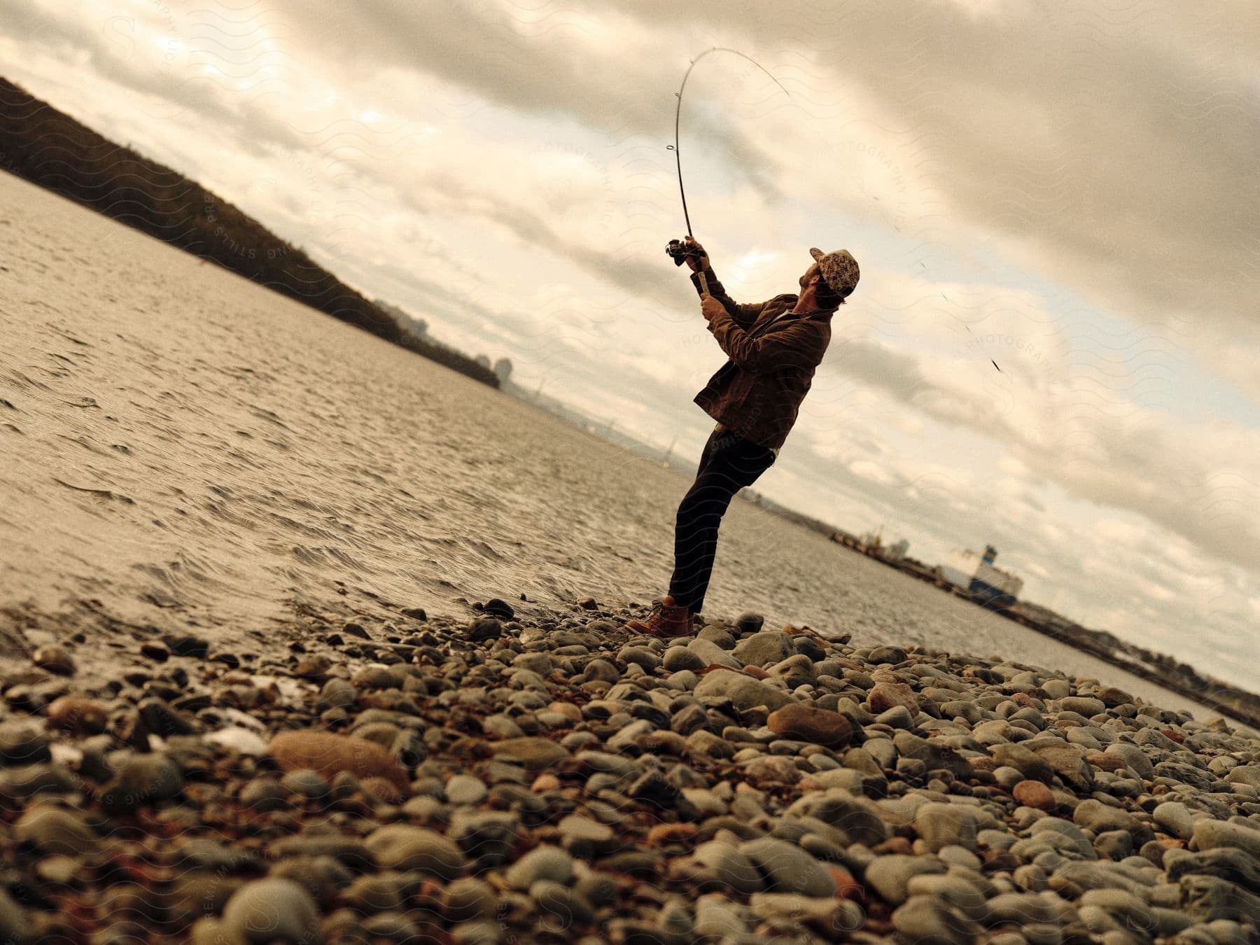 A man fishing off the bank of a river.