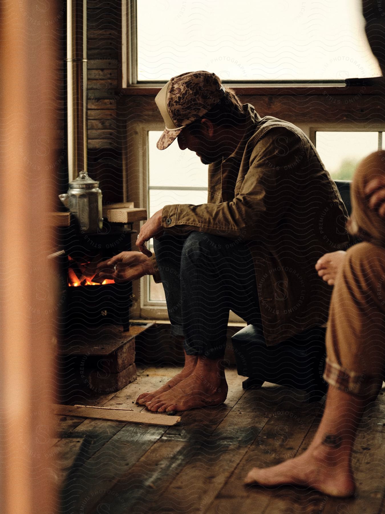 two men sitting by a fire warming themselves while barefooted du to cold