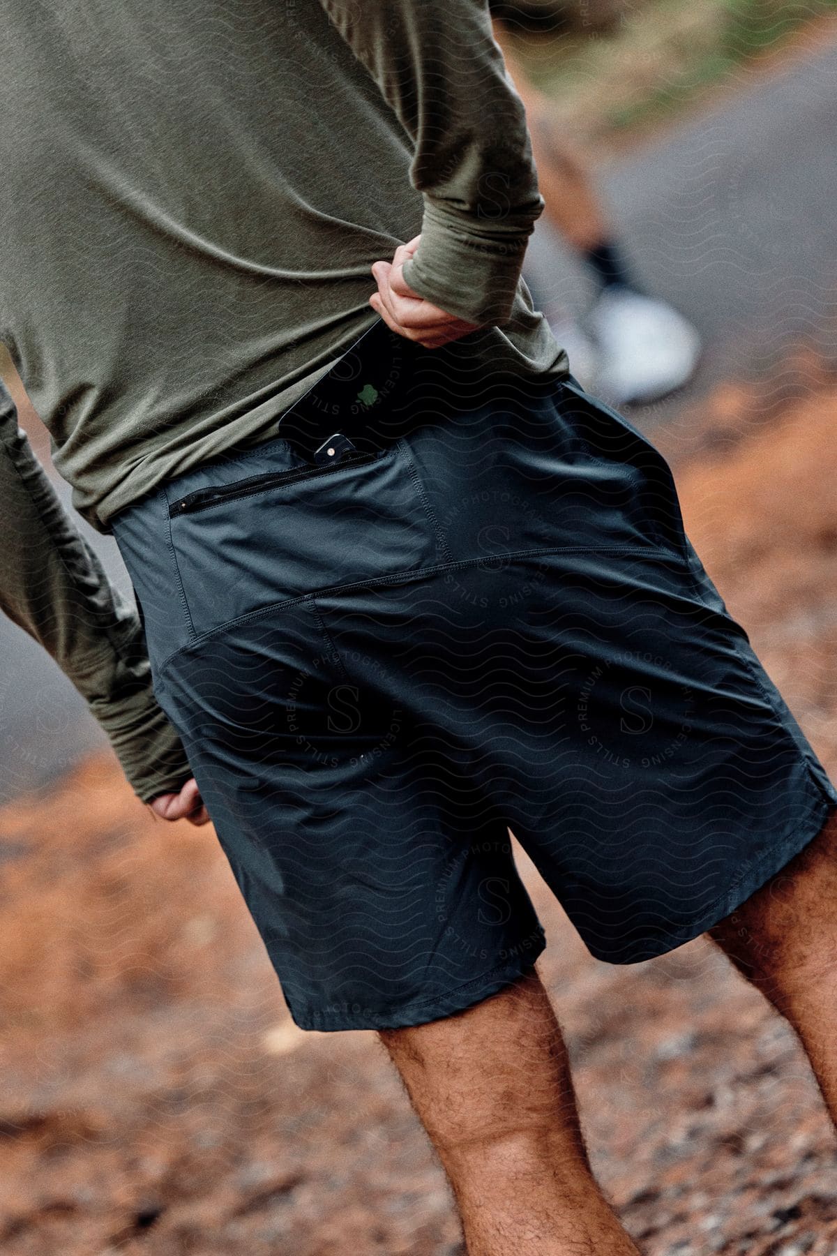 Man from behind wearing dark blue shorts with cell phone pocket