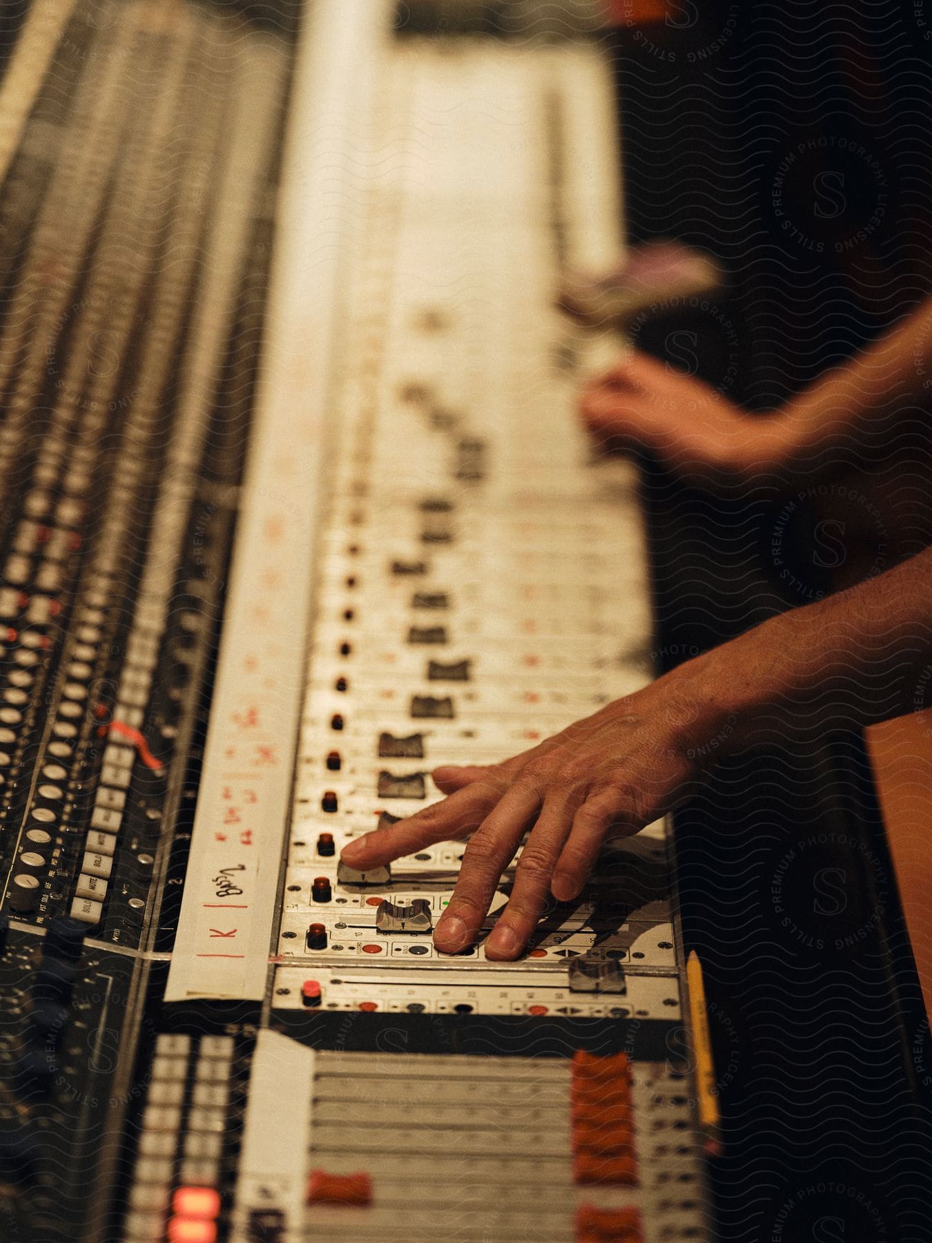 Adult hands work on a large, electronic soundboard.