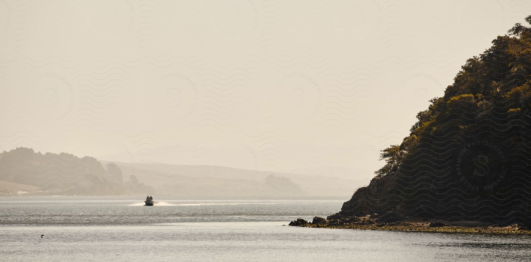 A view of the coast with water and some hills next to it.