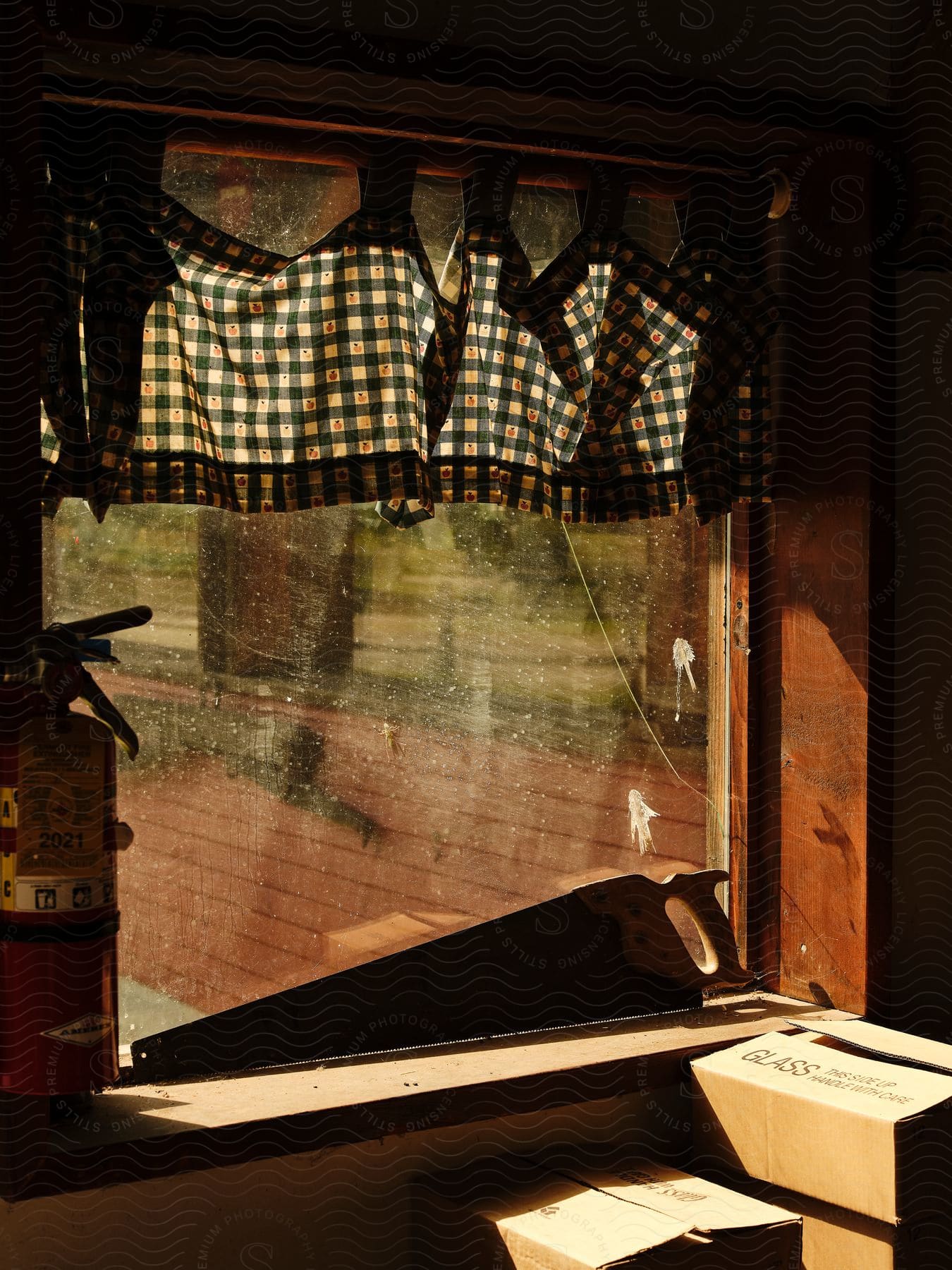 A view out of a window in a house with curtains at the top of the window.