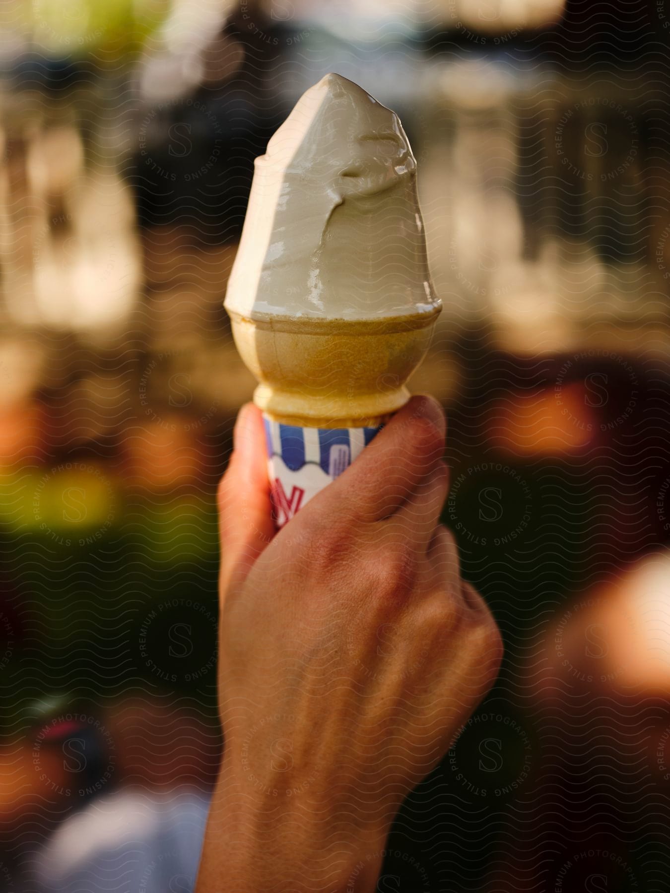 Person holds ice cream filled paper-wrapped cone.