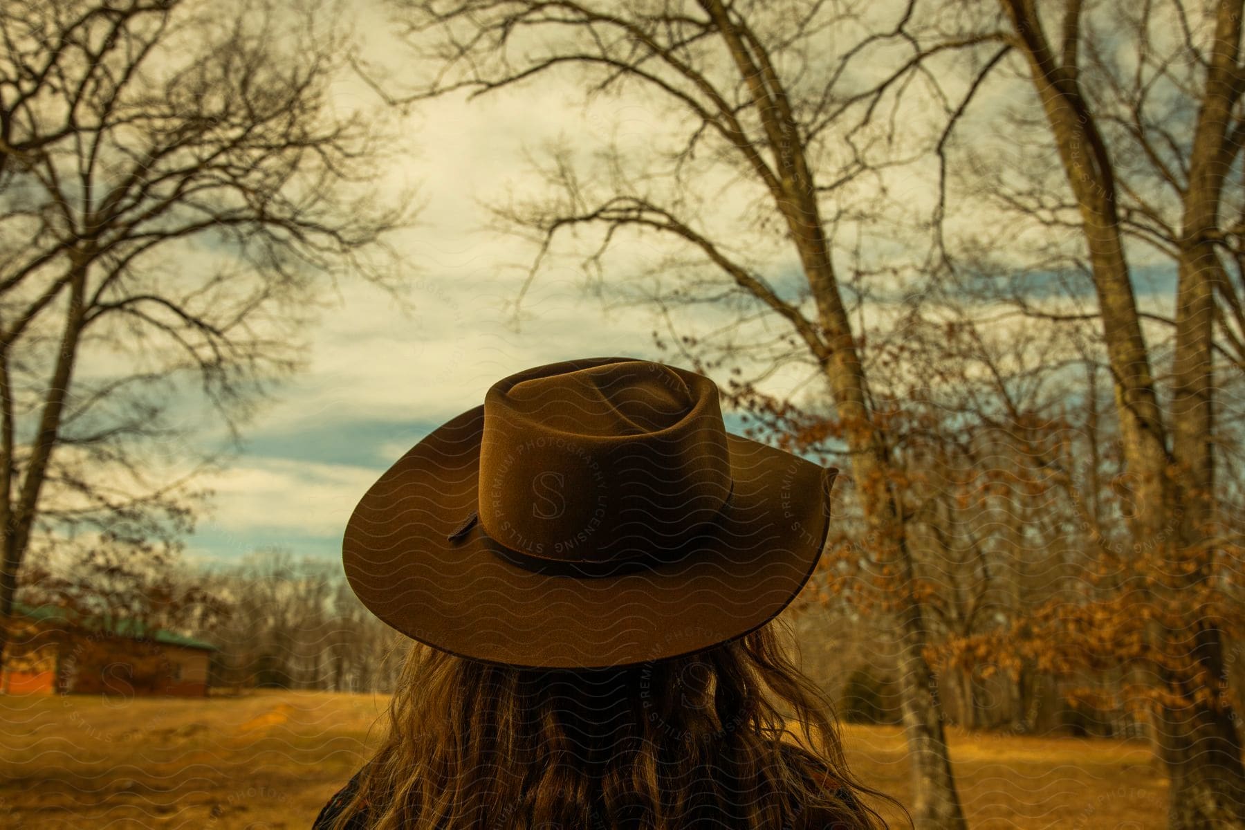 a female in a rural setting wearing a cowboy hat during the day