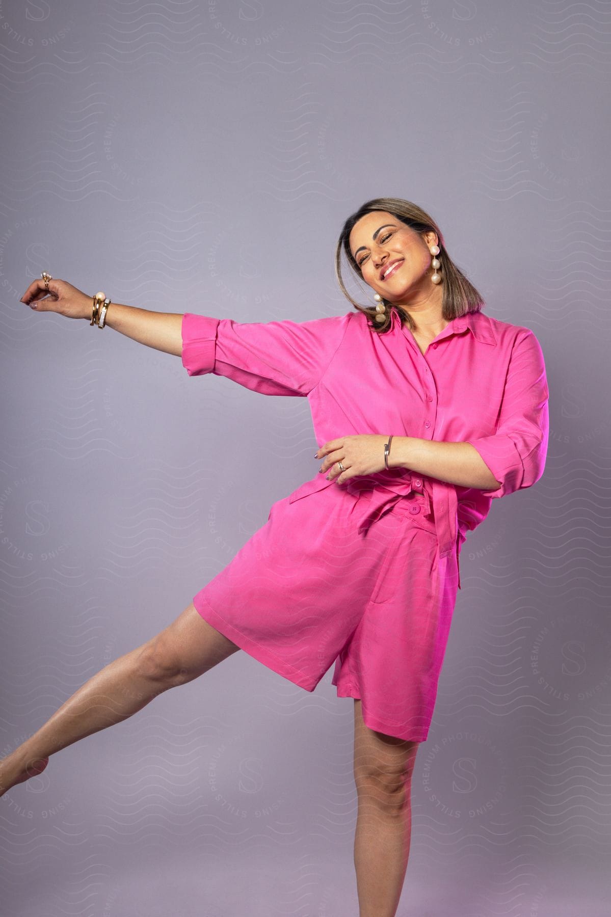 A smiling woman wearing a pink jumpsuit during a photo shoot.