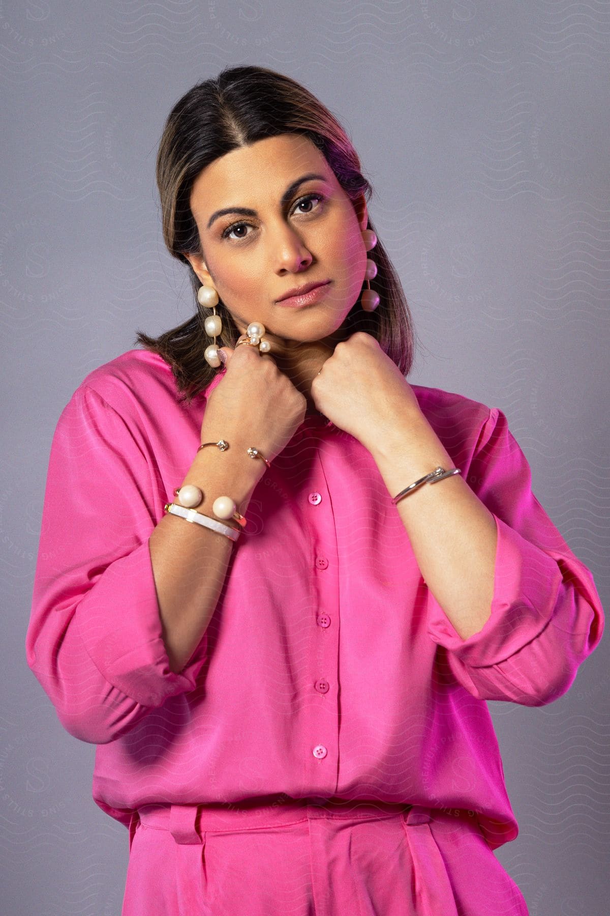 a woman wearing jewelries and earrings place her hands on her neck