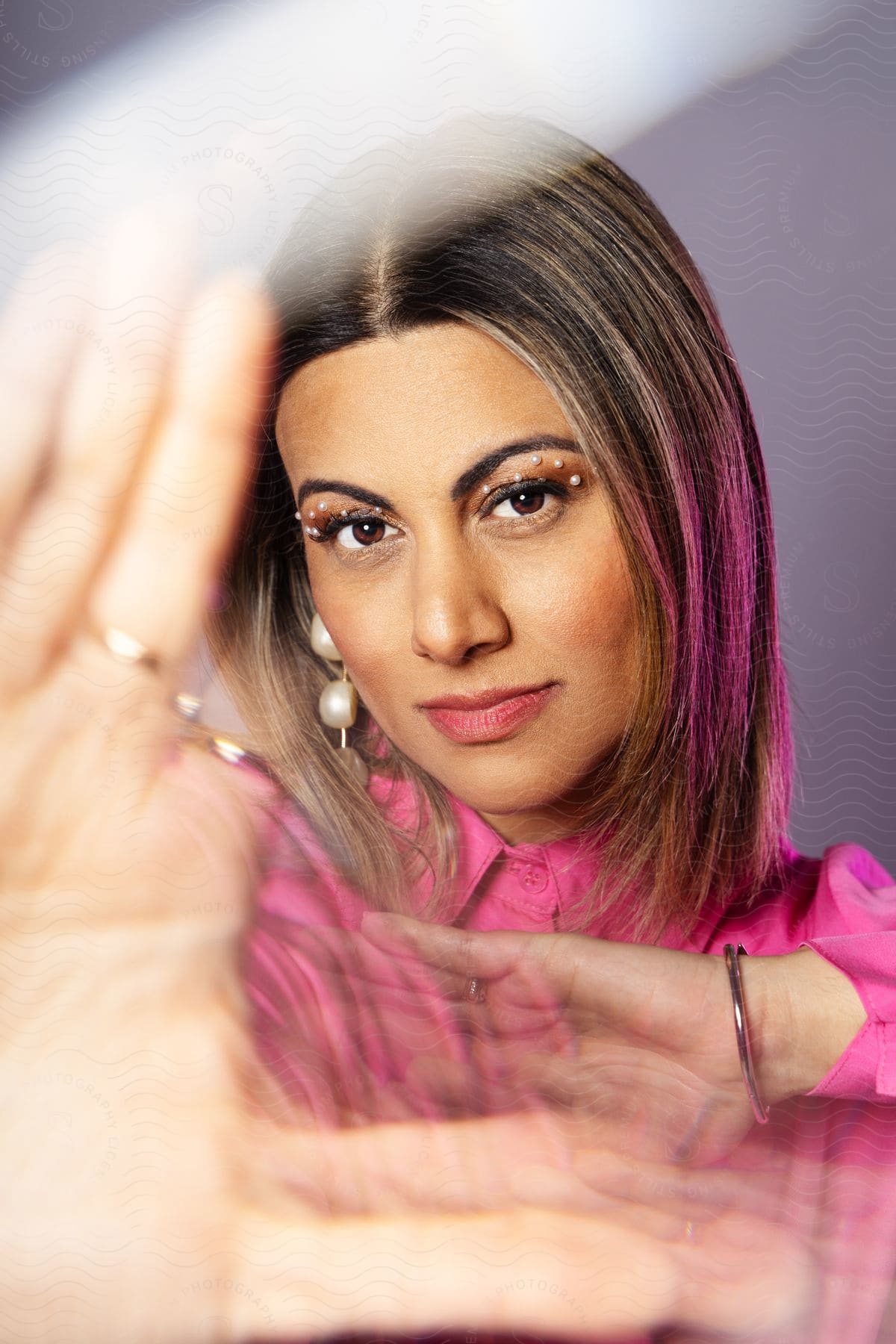 Portrait of a woman with makeup and palms facing forward.