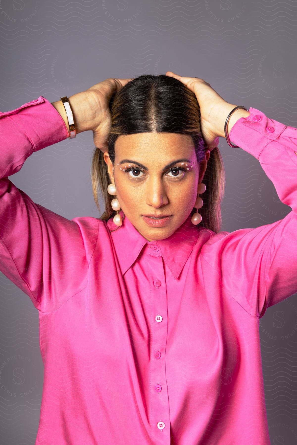 young lady in purple shirt poses with both hands placed on the head