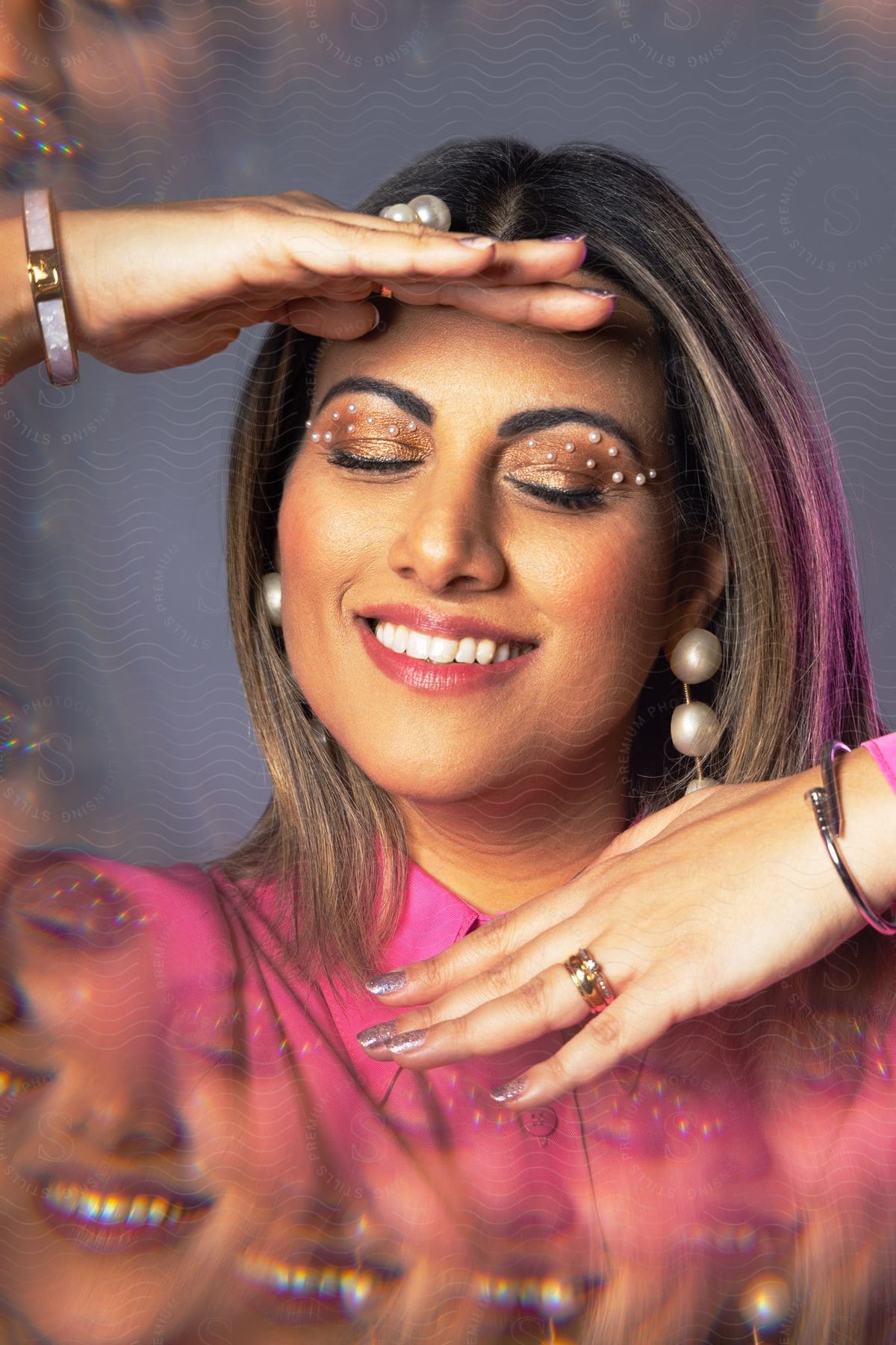 Woman smiles while wearing elaborate makeup including seed pearls.