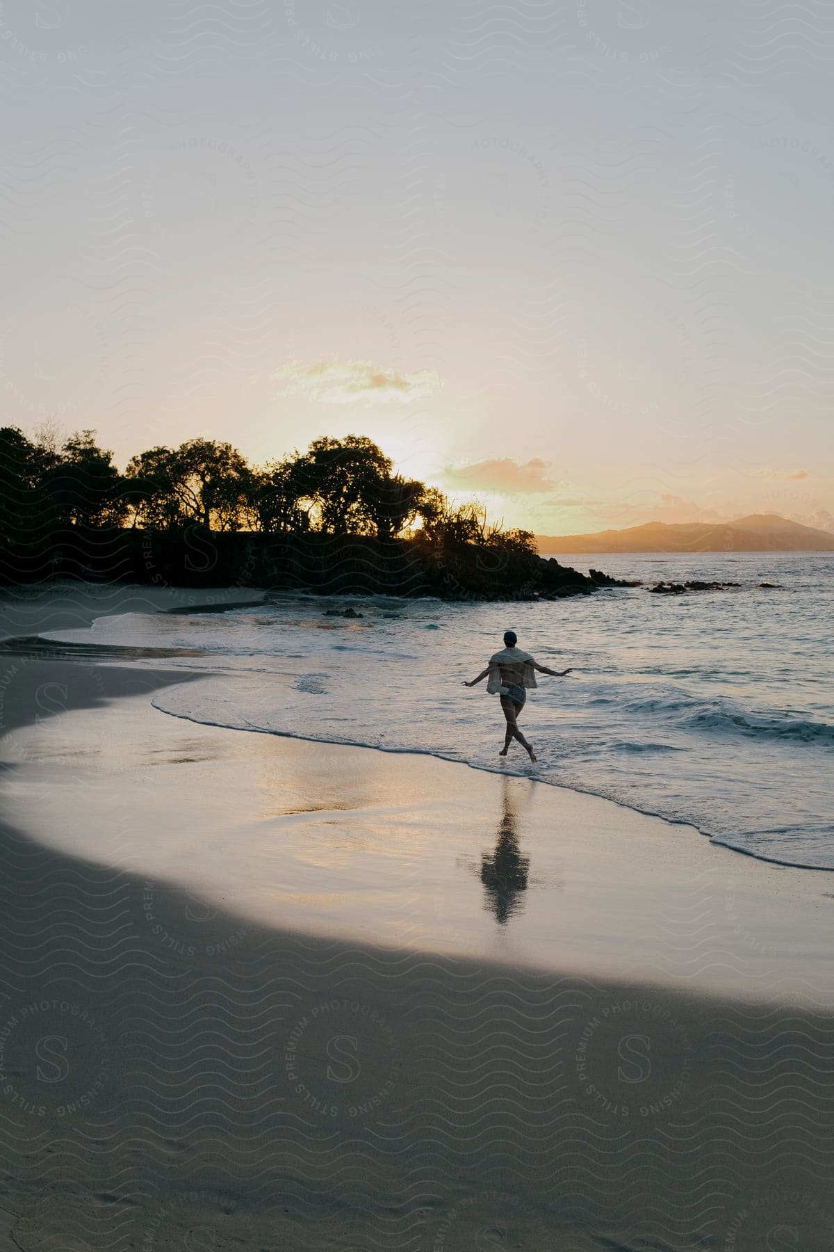 Woman running along the seashore and on the beach sand with the sunrise on the horizon