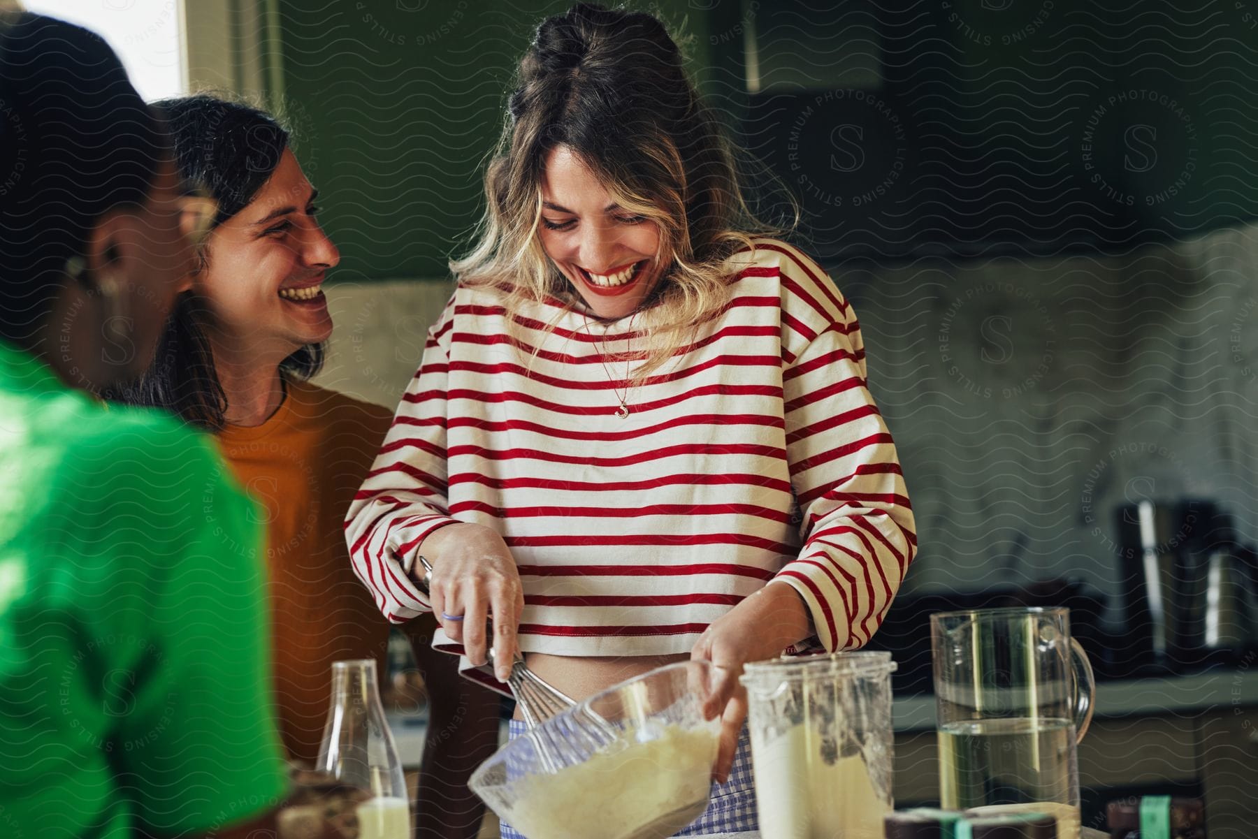 Three women cooking in the kitchen while smiling.