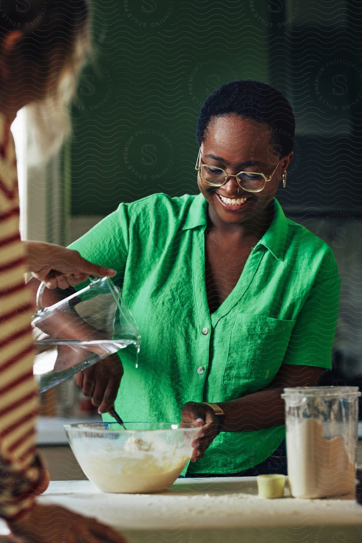 A woman mixing ingredients in a pan in the kitchen.