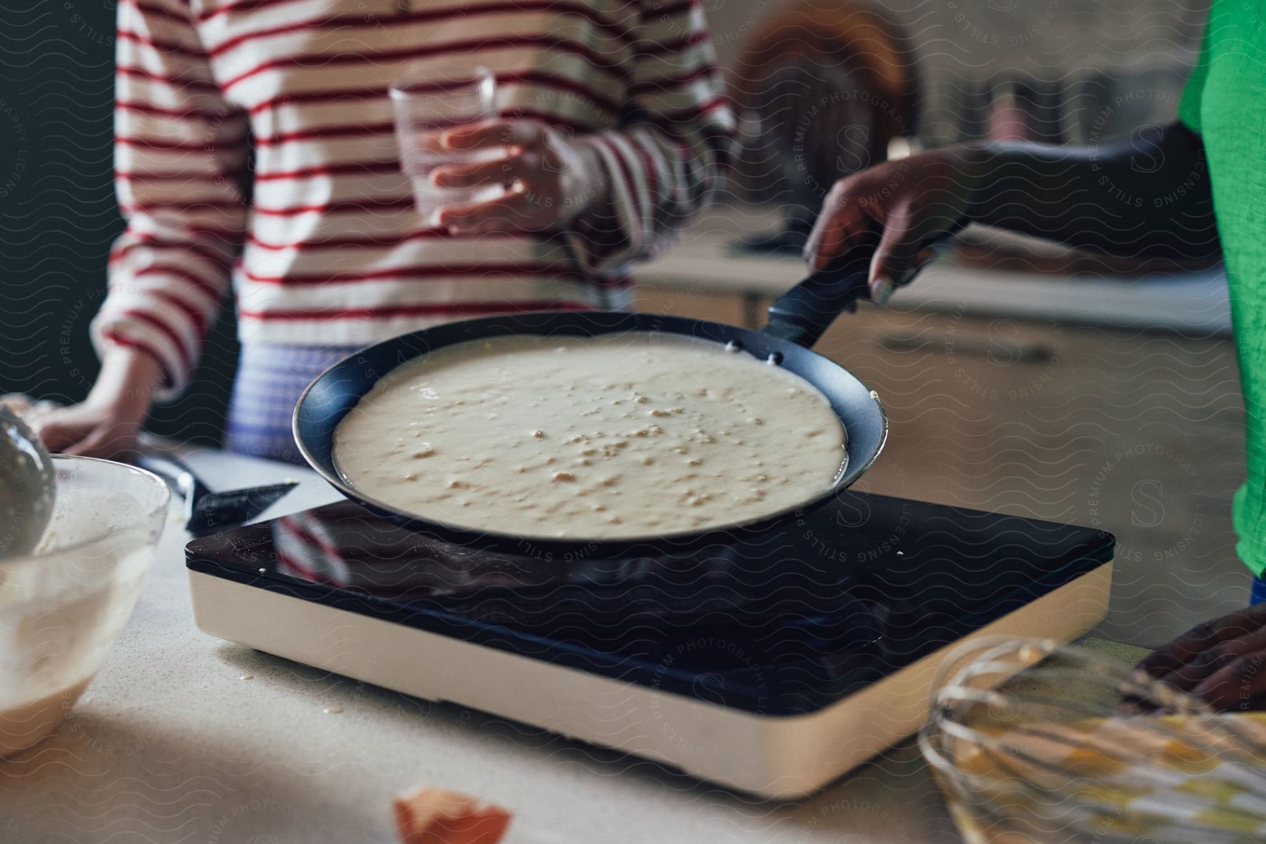 Two people making a large crepe on a stovetop