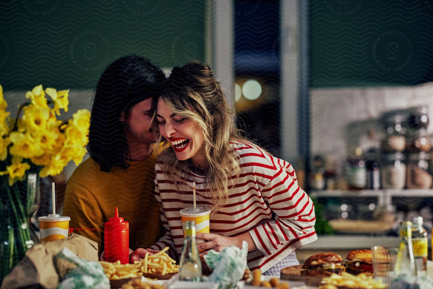 A man and woman are standing over a table of food laughing