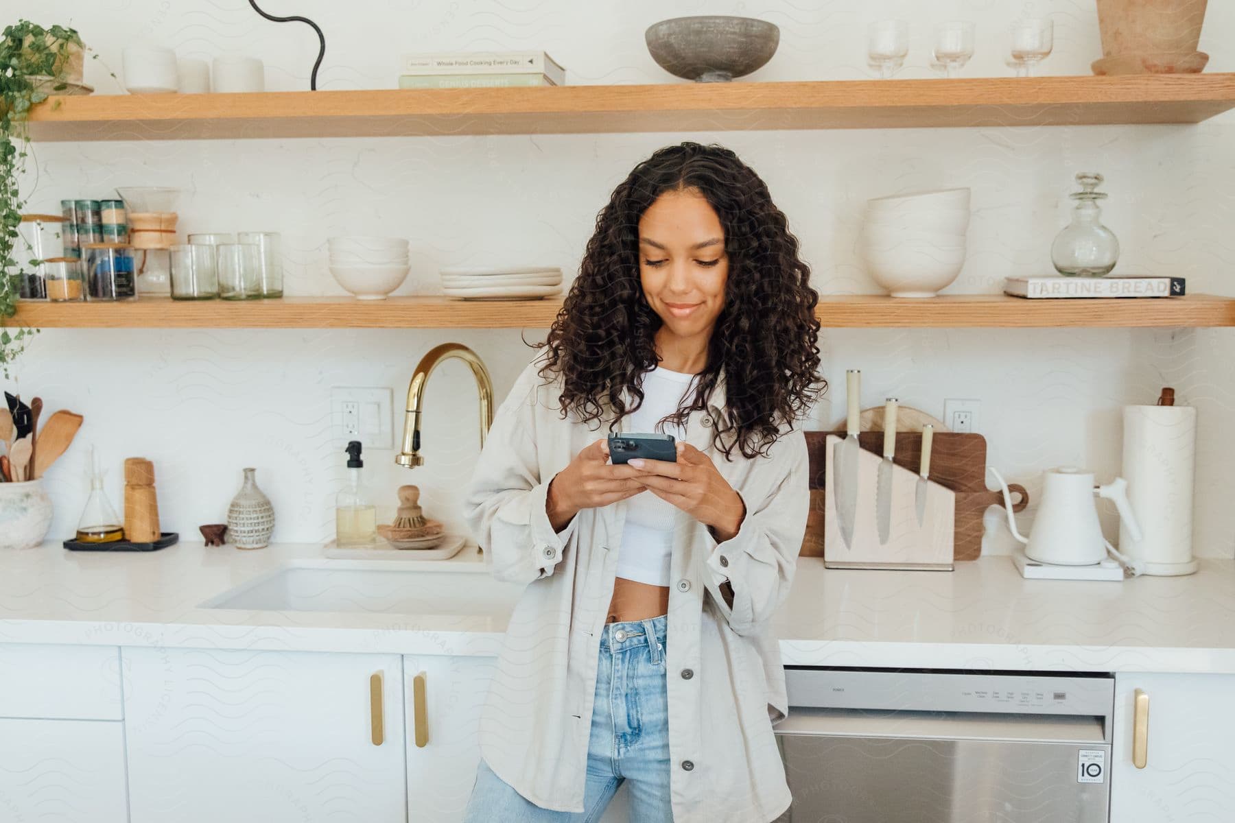 A woman standing in a room modeling clothes on a phone.