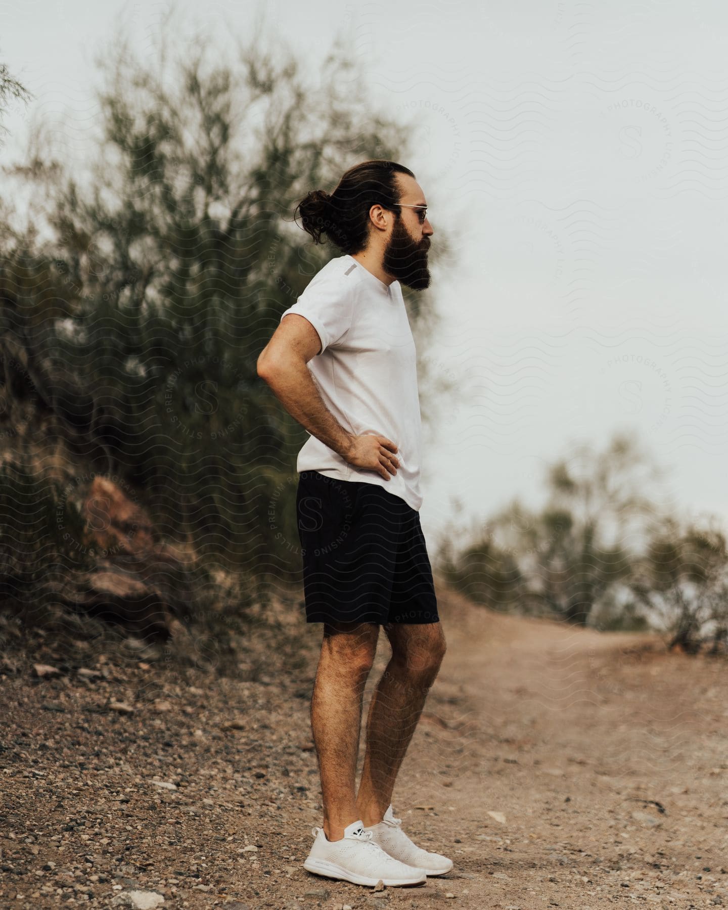 Fashionable man in shorts and white shirt on a hill.