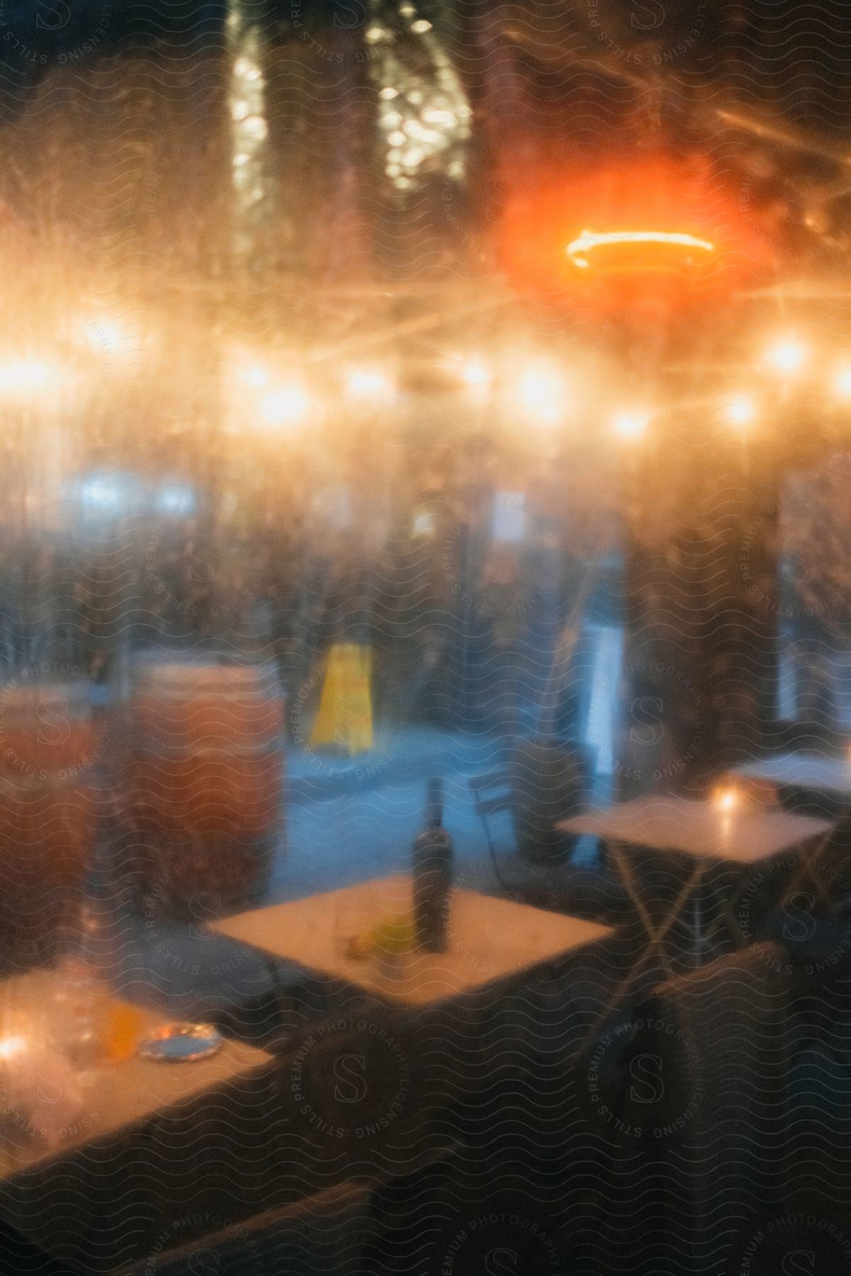 View from outside looking through the steamed window of a restaurant with candles on tables and lights on