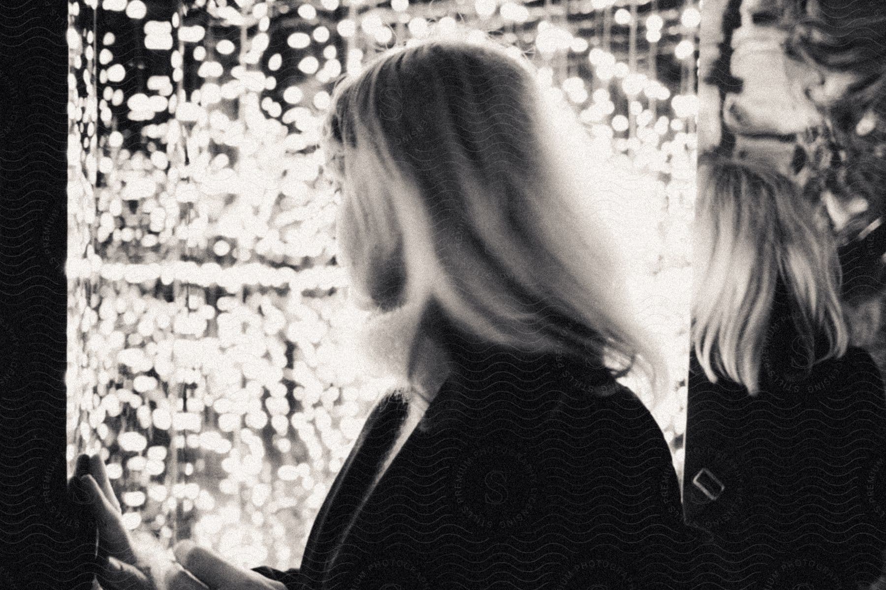 A blonde woman in a room lit by small lamps.