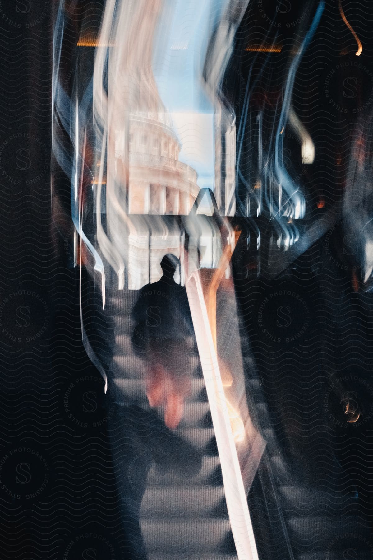 Blurred motion of a man's silhouette going down an escalator.