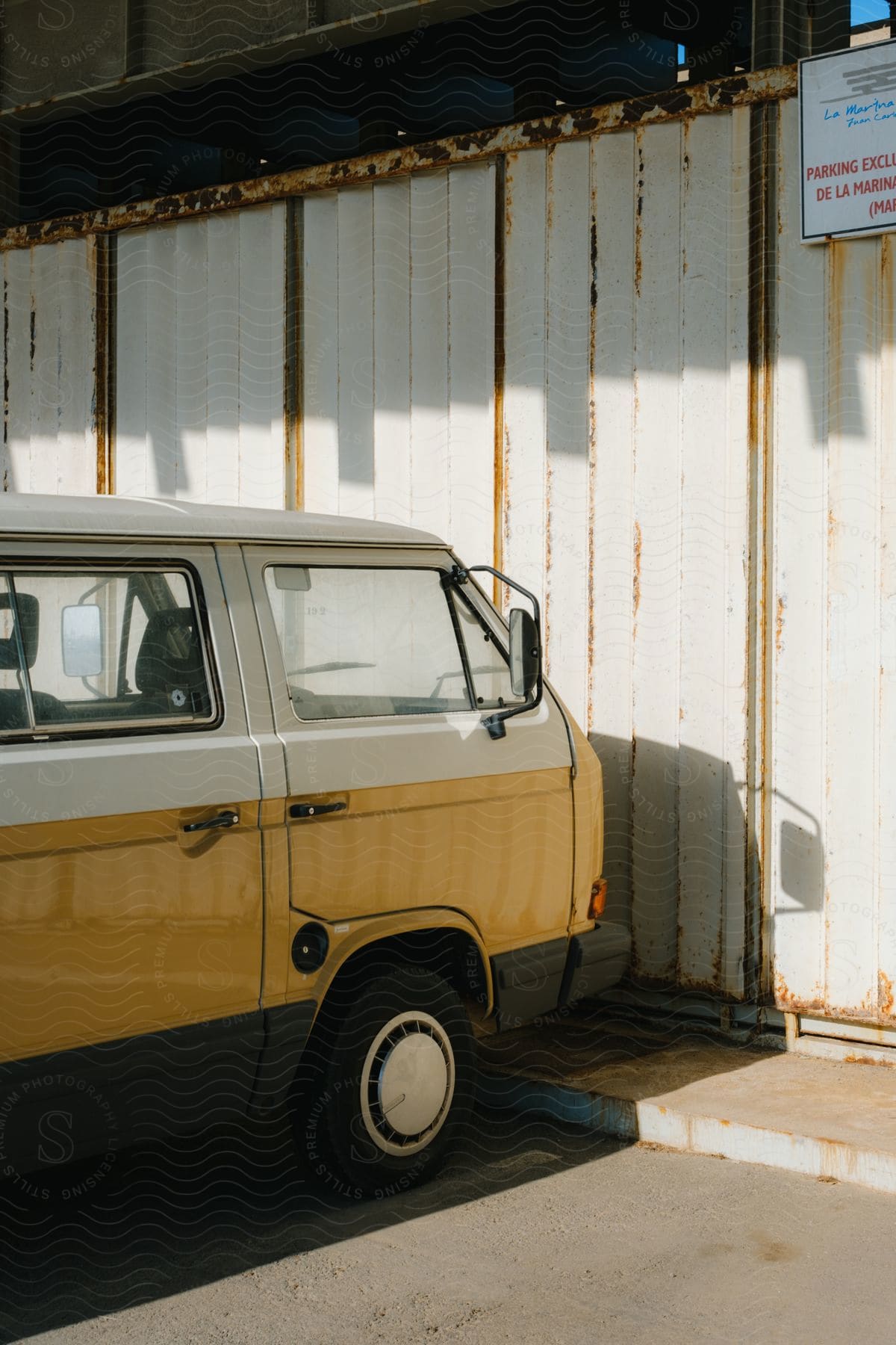 Parked minivan sits  in a parking space near building wall.