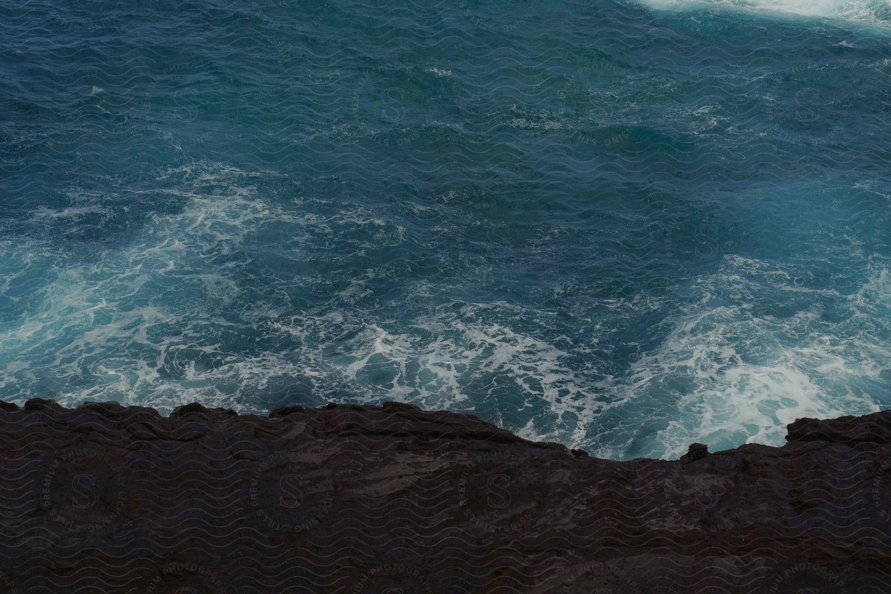 View looking down at a ledge along the coast as waves roll in