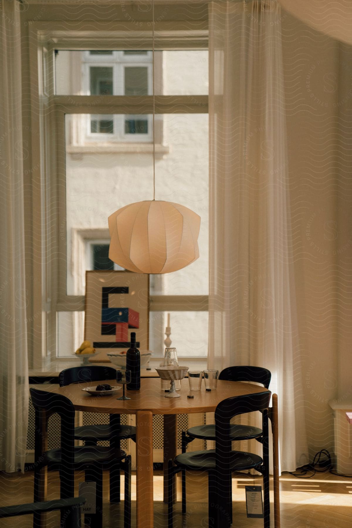 A table with a bottle and glasses of wine in the living room of an apartment.