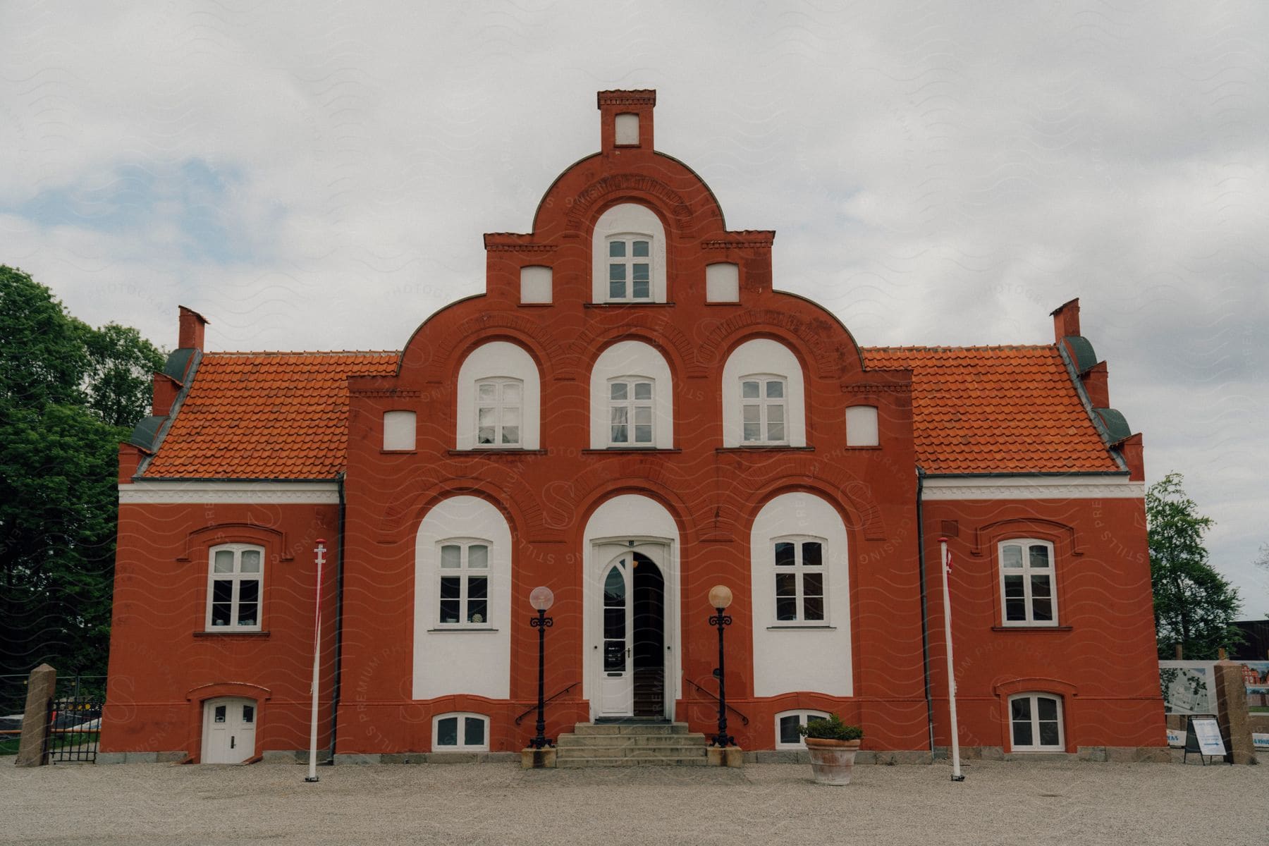 A church with old architecture painted red in a neighborhood during the day.