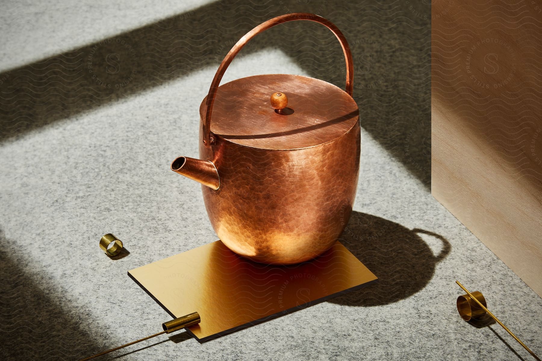 A copper teapot and brass ornaments on a golden sheet shine in the sun