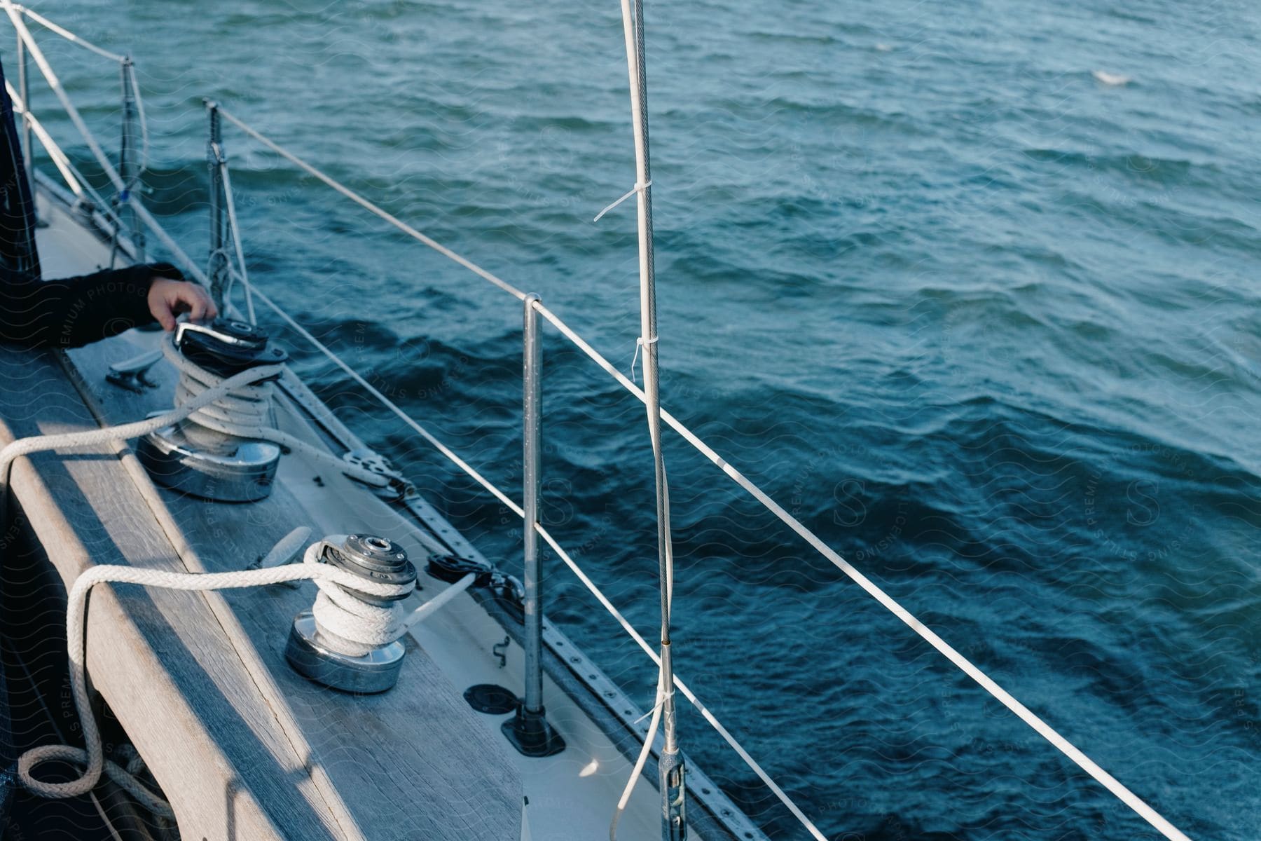 A person's hand is near rope on the side deck of a boat