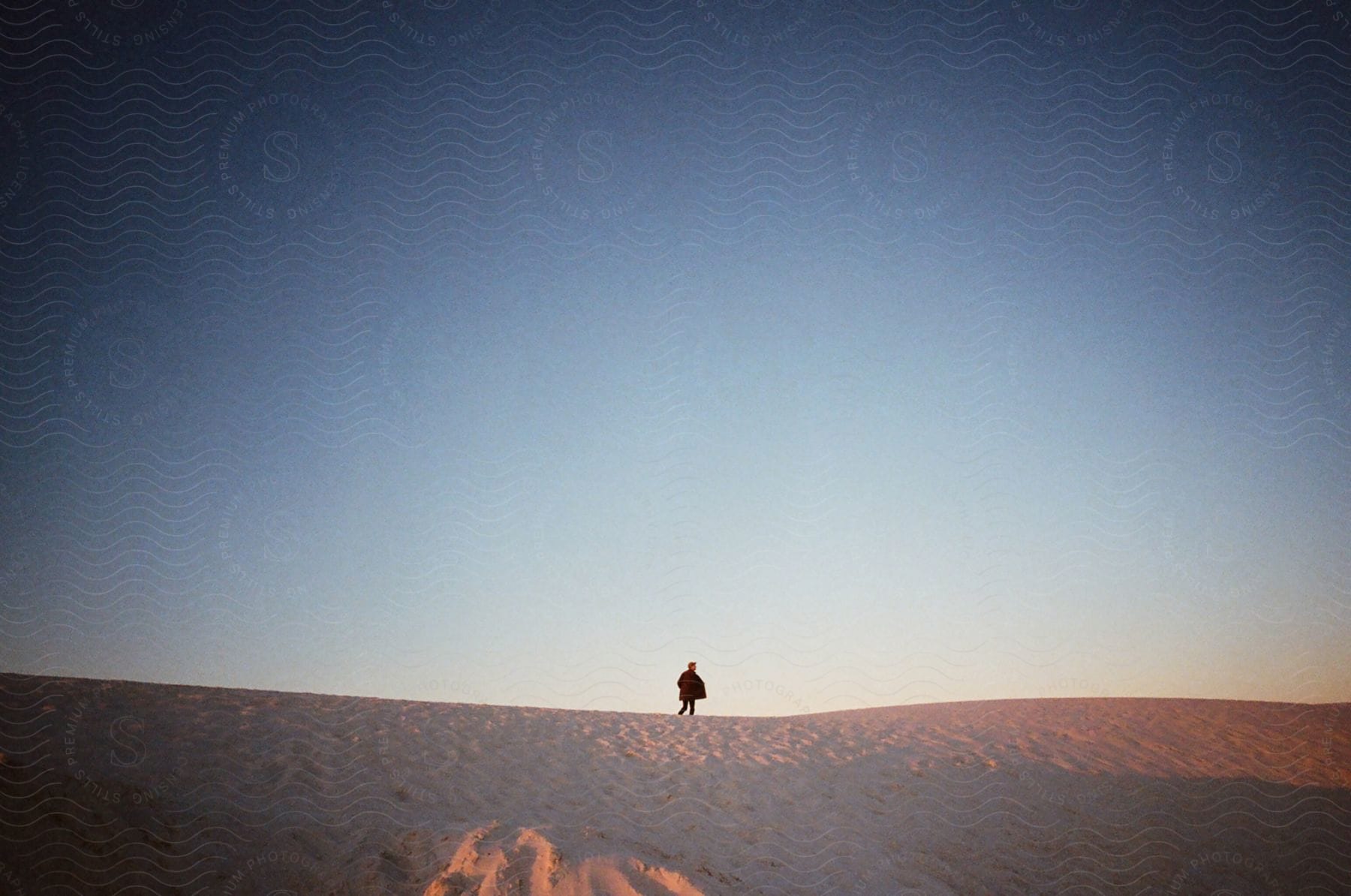 Desert landscape on a cloudless day with a person on the sand