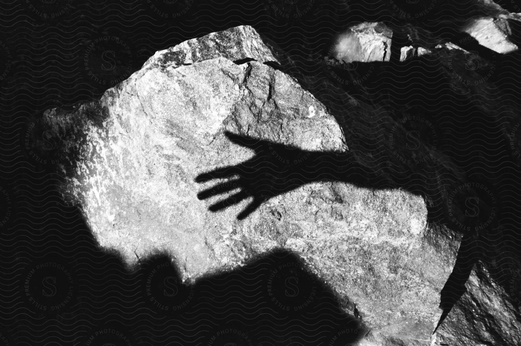 The shadow of a person's hand over a rocky ground