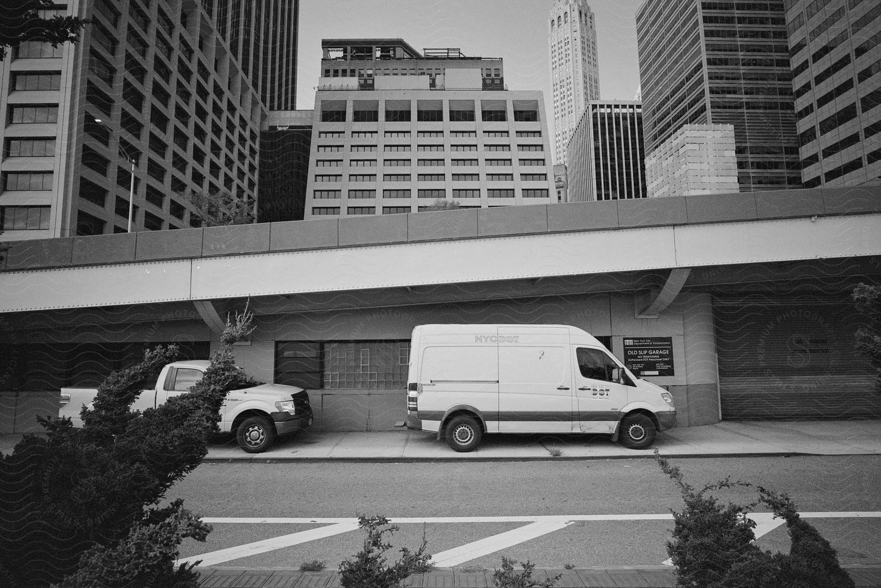 A van and a pickup truck parked on a street in the metropolitan city during the day.