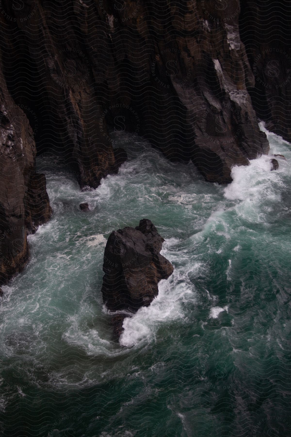 Waves splash against rocks at the foot of a cliff along the coast