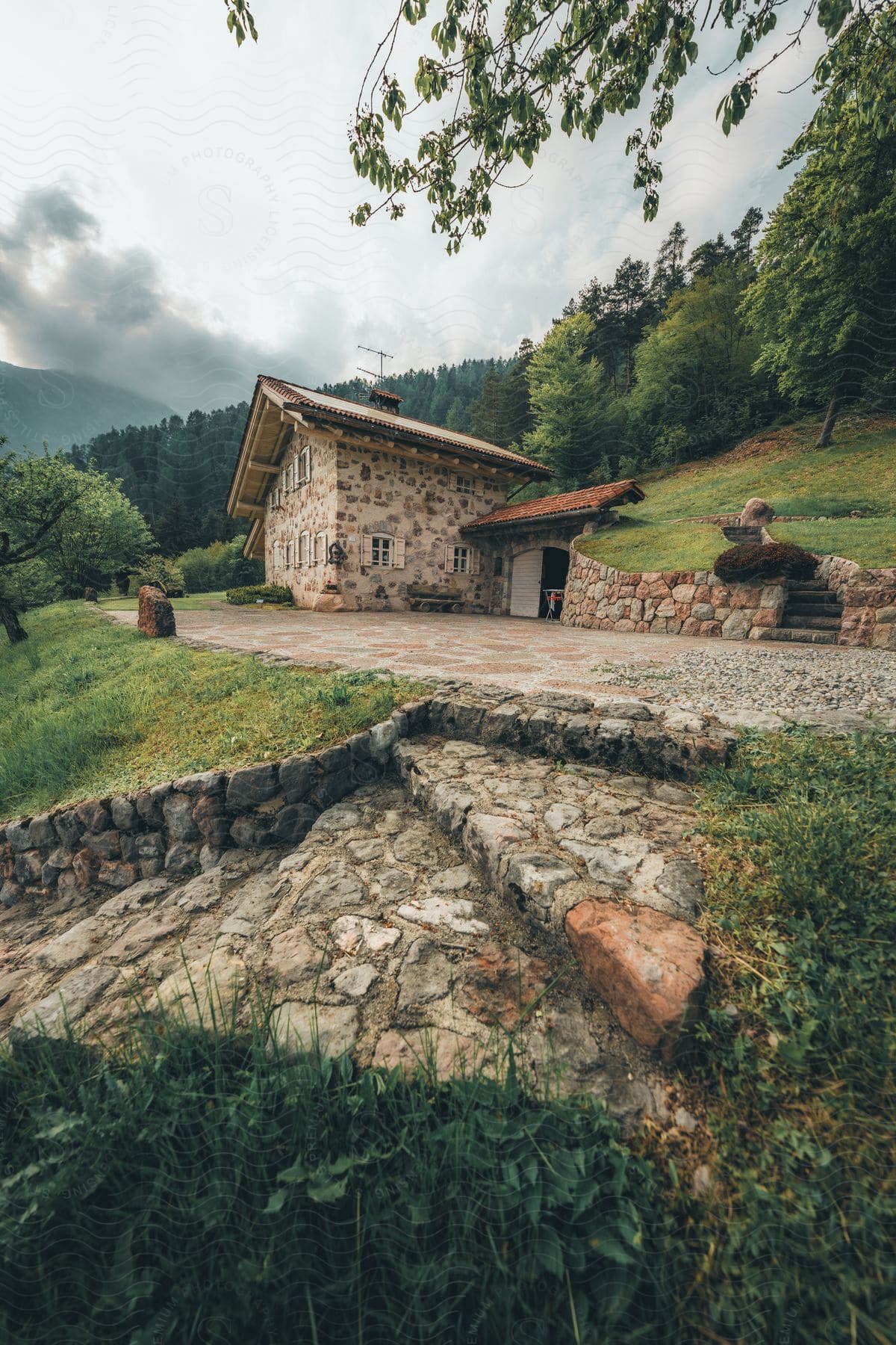 House with stone texture on a hill in the mountains with conifers around on a cloudy day