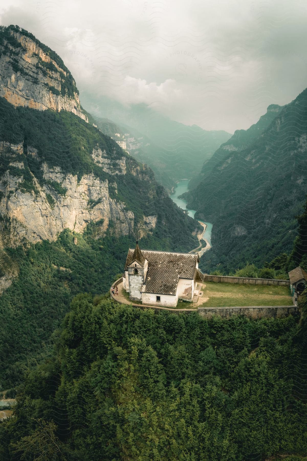 Church on the cliff of a hill surrounded by mountains on a cloudy day