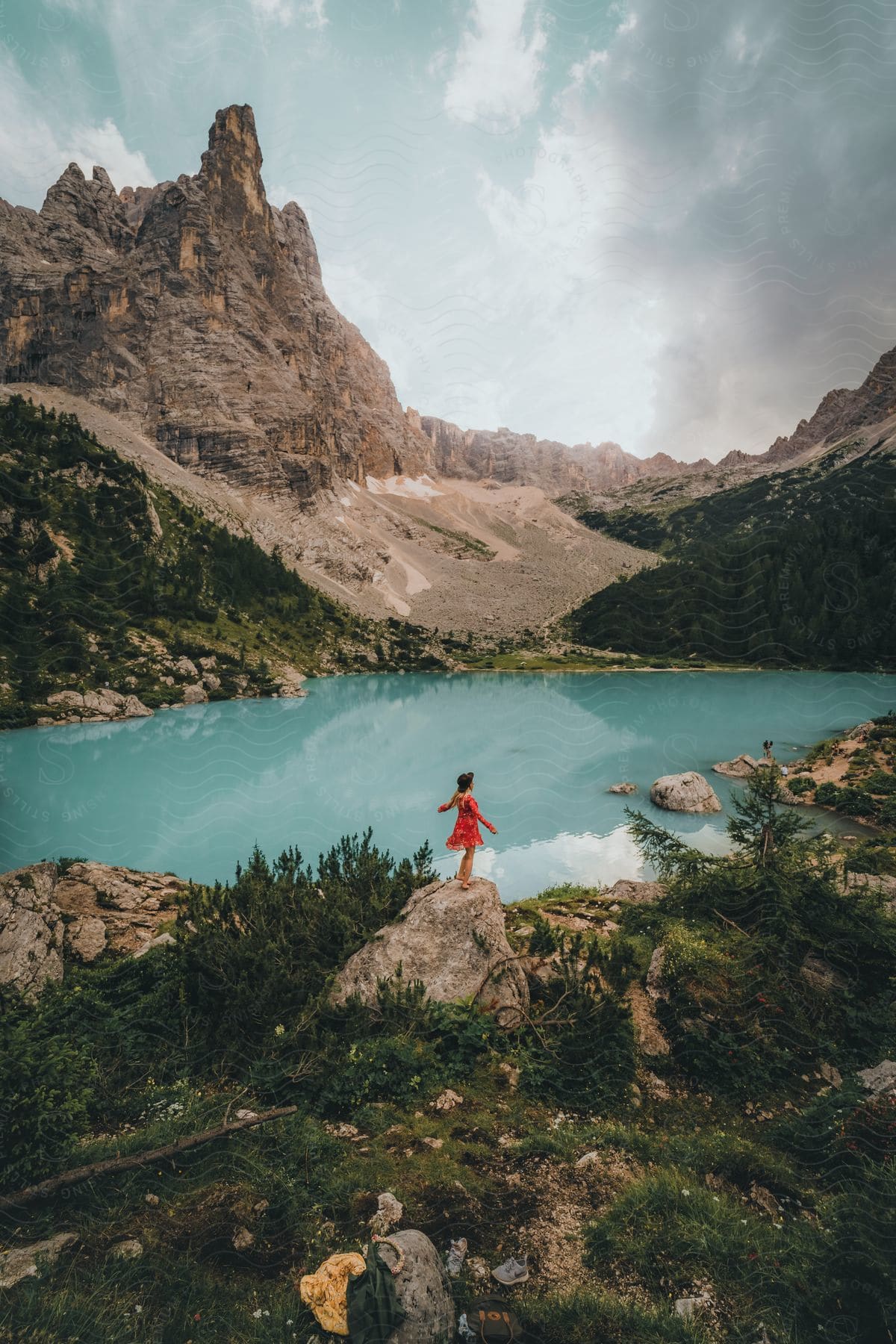 A woman standing on a rock next to a lake in the mountains