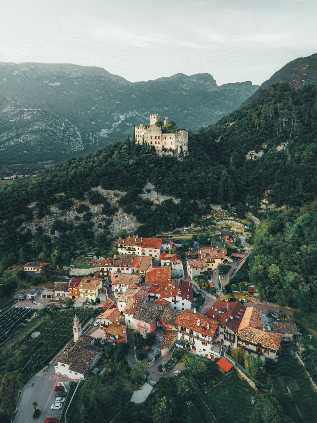 Aerial panorama of a city on a hill with a castle on the peak and surrounding mountains with vast vegetation