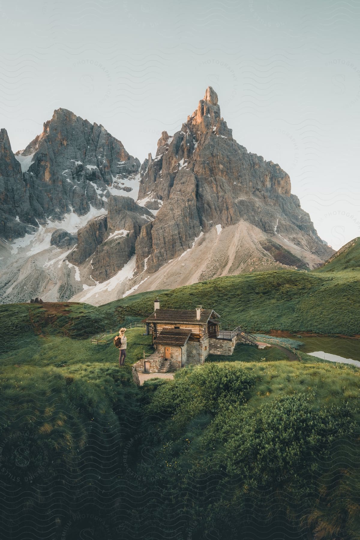 a person standing near a small cabin with mountains