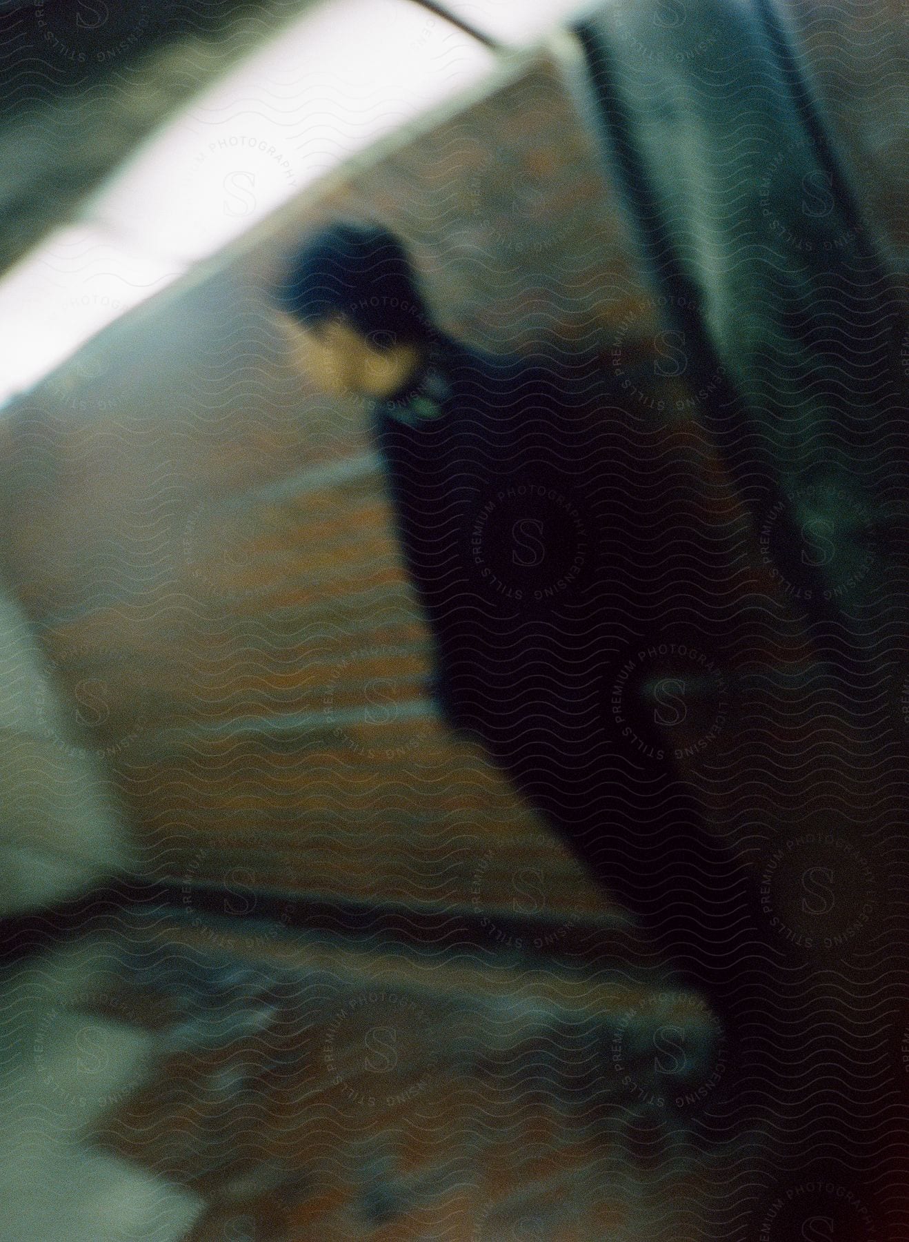 A young man is standing against a brick wall