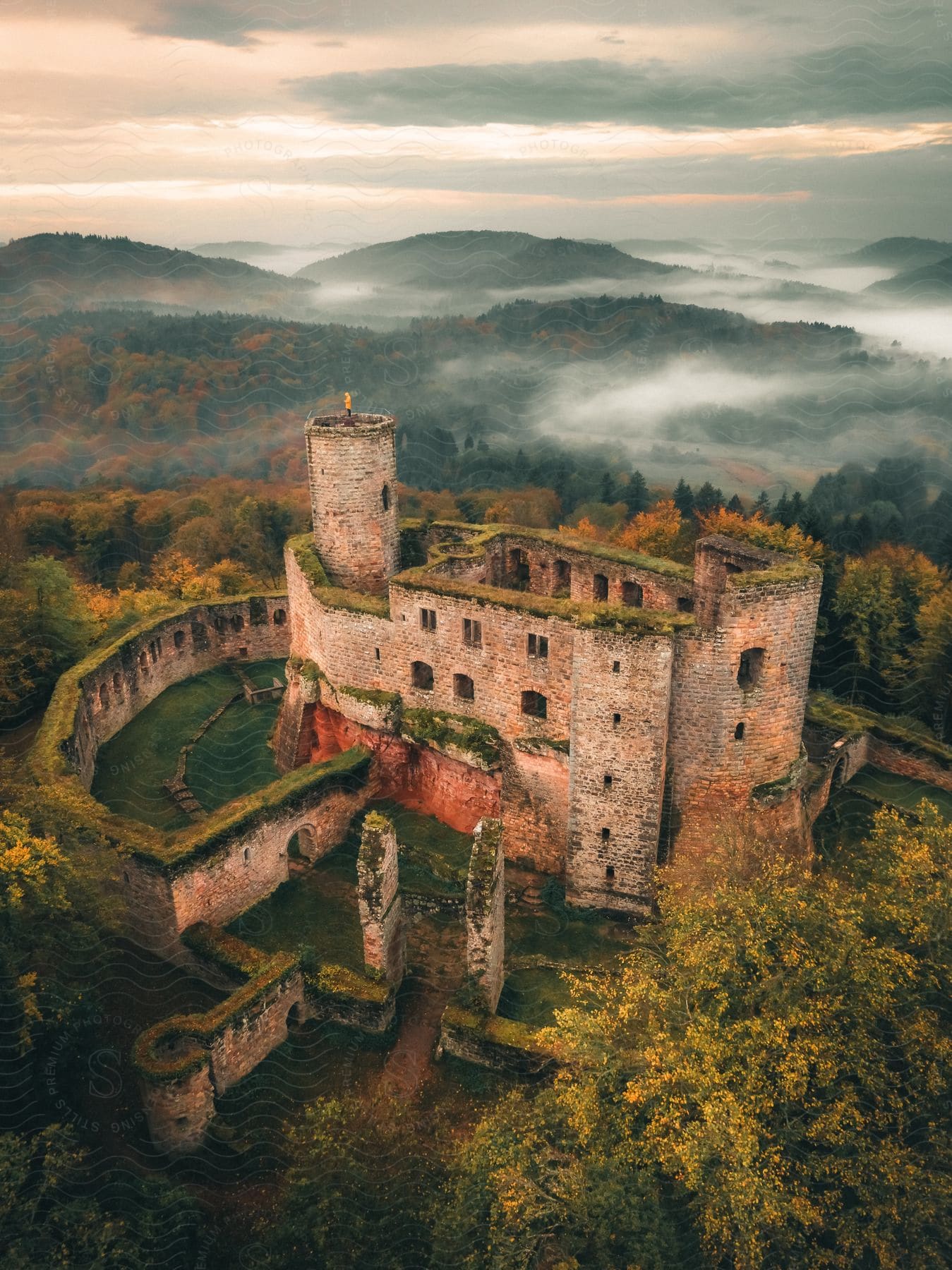 Ruins of a medieval castle in the middle of forest covered hills on a fall morning.