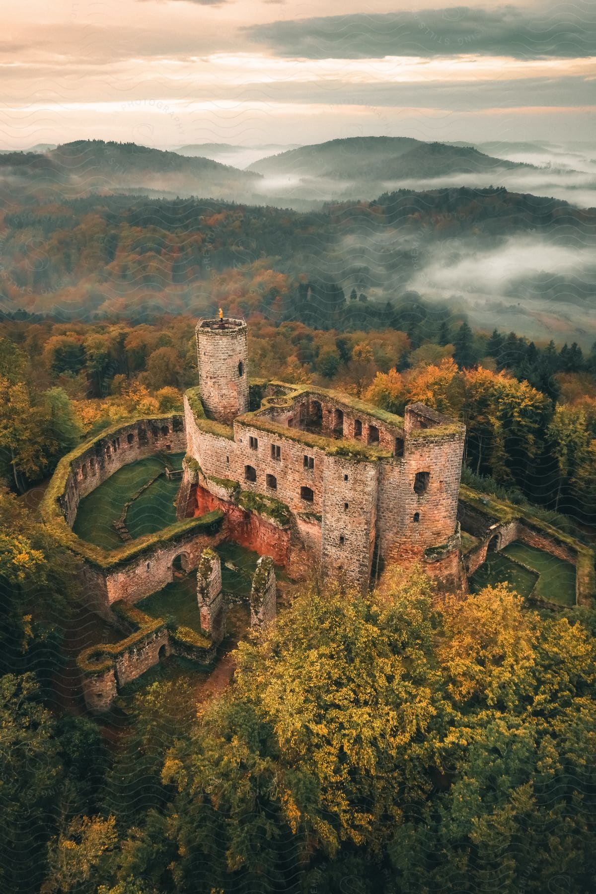 Castle surrounded by trees in fall colors and mountains in the distance