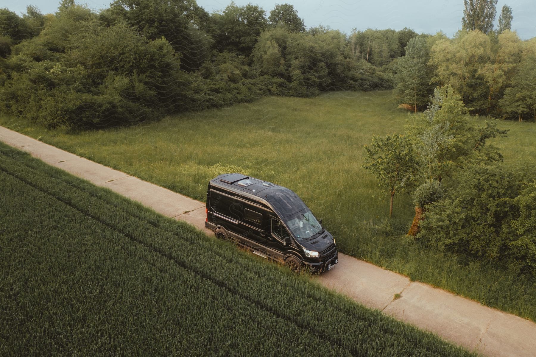 Van traveling on a narrow road through a wooded rural area