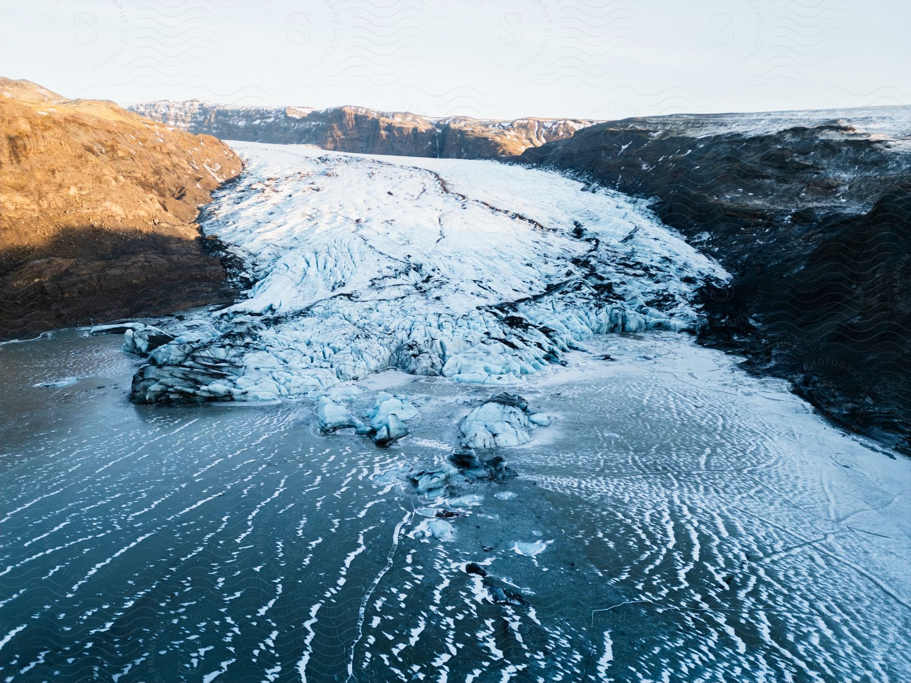 Ice covered water with snow on mountains along the coast