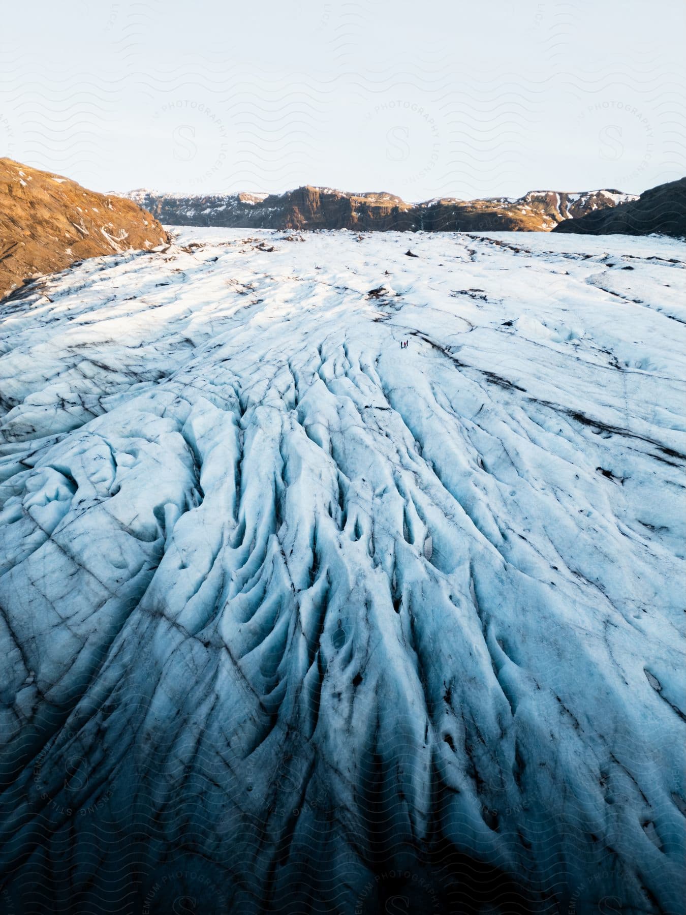 Aerial of polar ice caps between rocky mountains in winter.