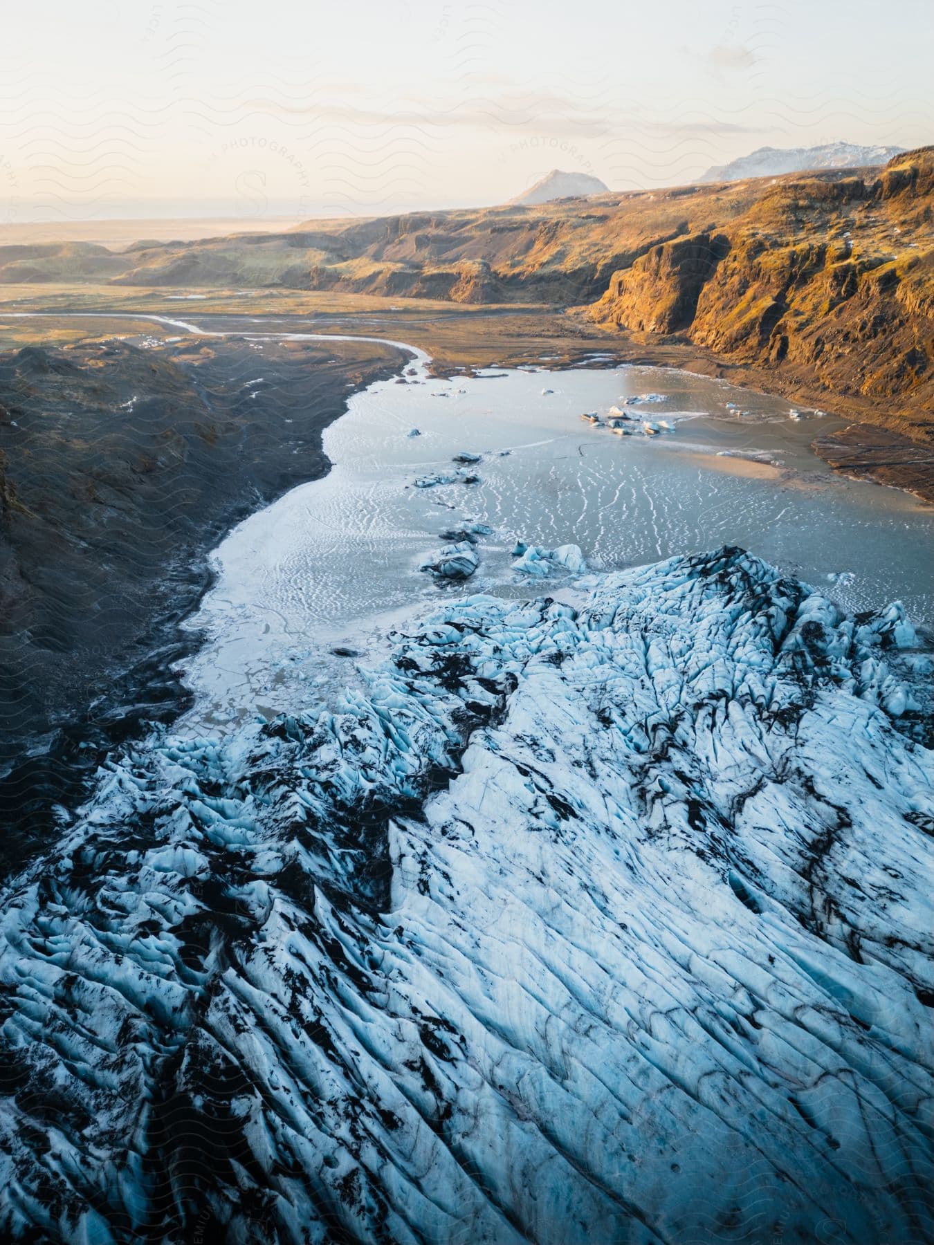 Aerial of mountains and a river with ice caps during the day.
