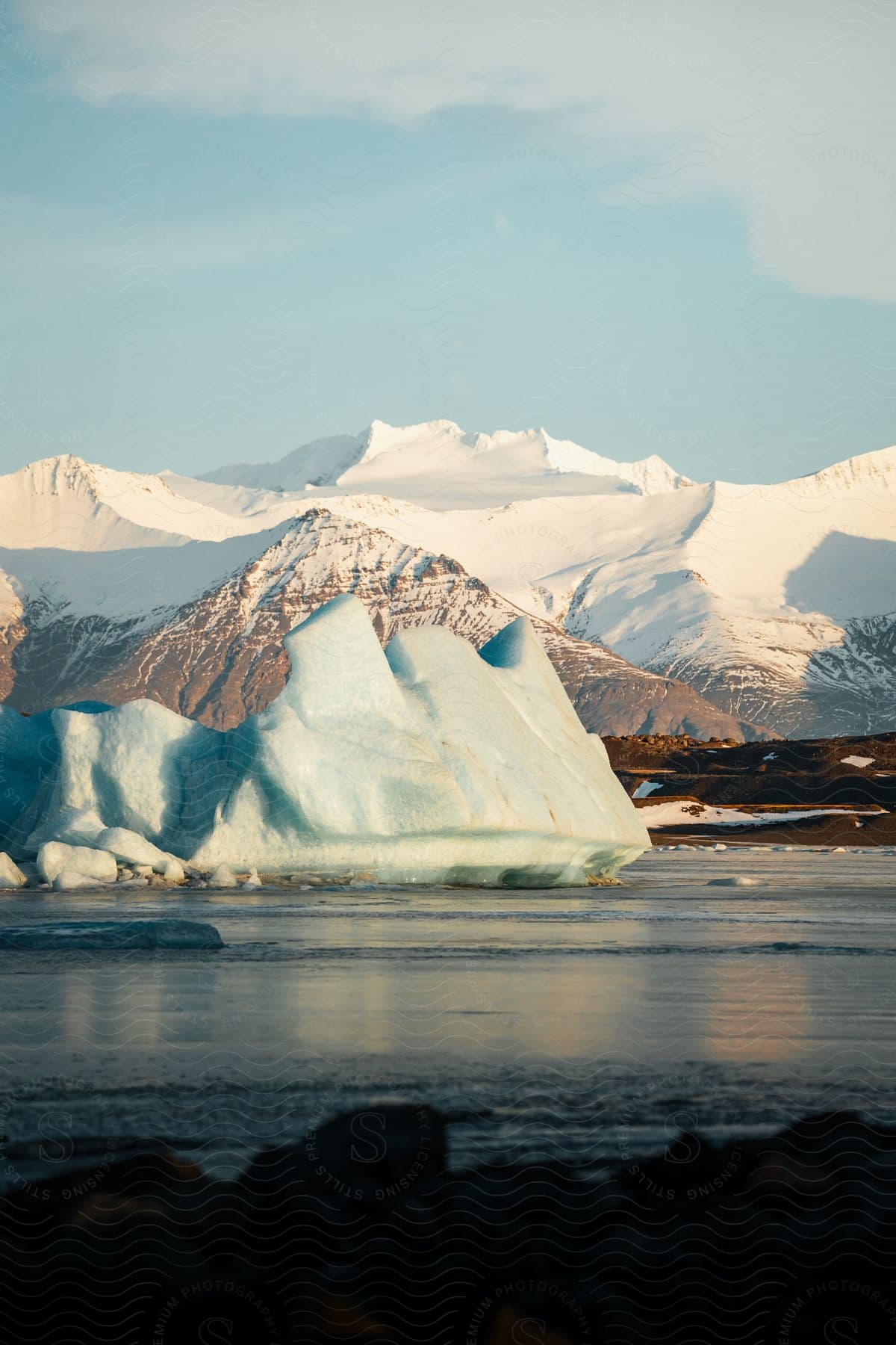 Melting iceberg in the water with snow covered mountains along the coast