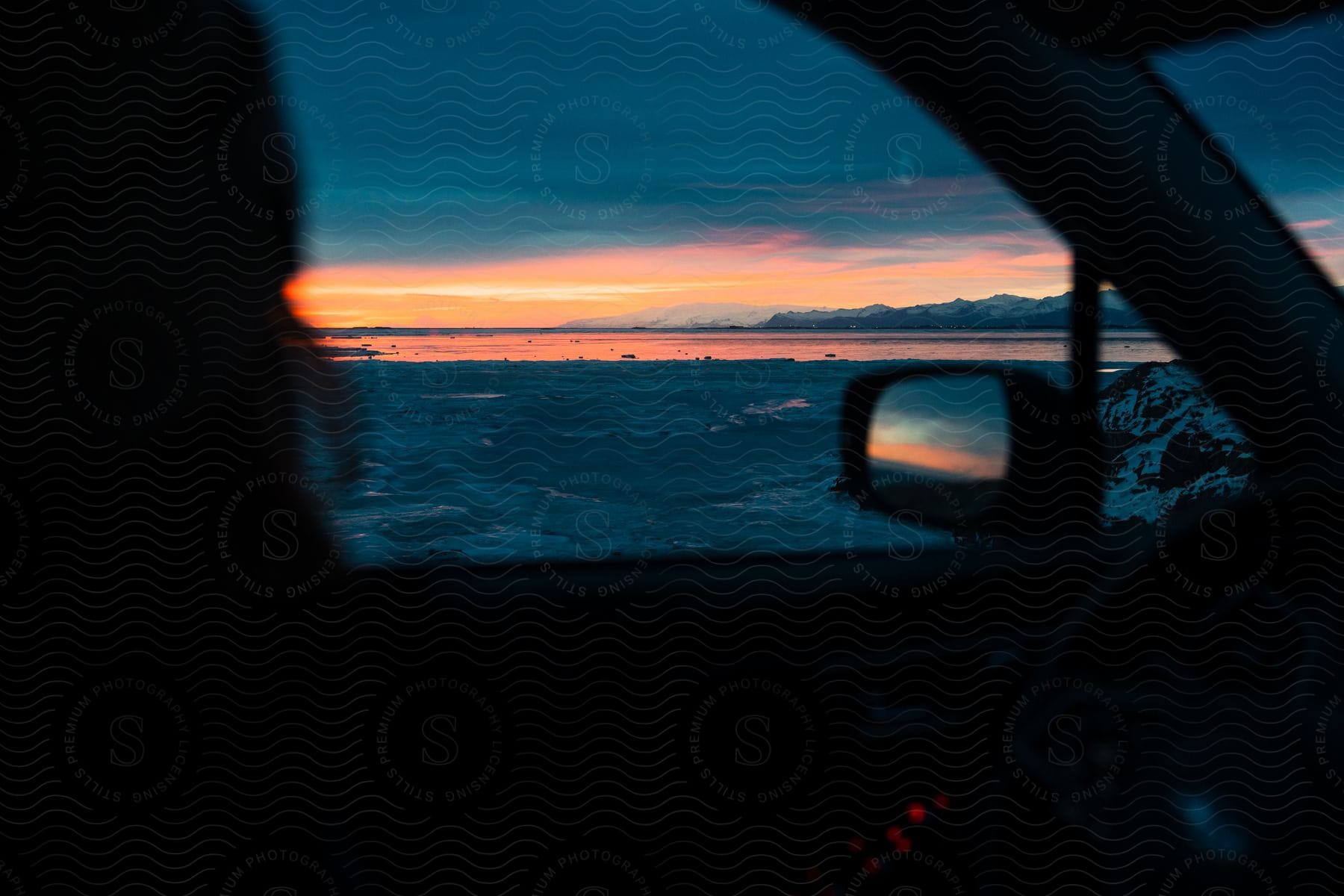 A person in a car watching the sea landscape at sunset.