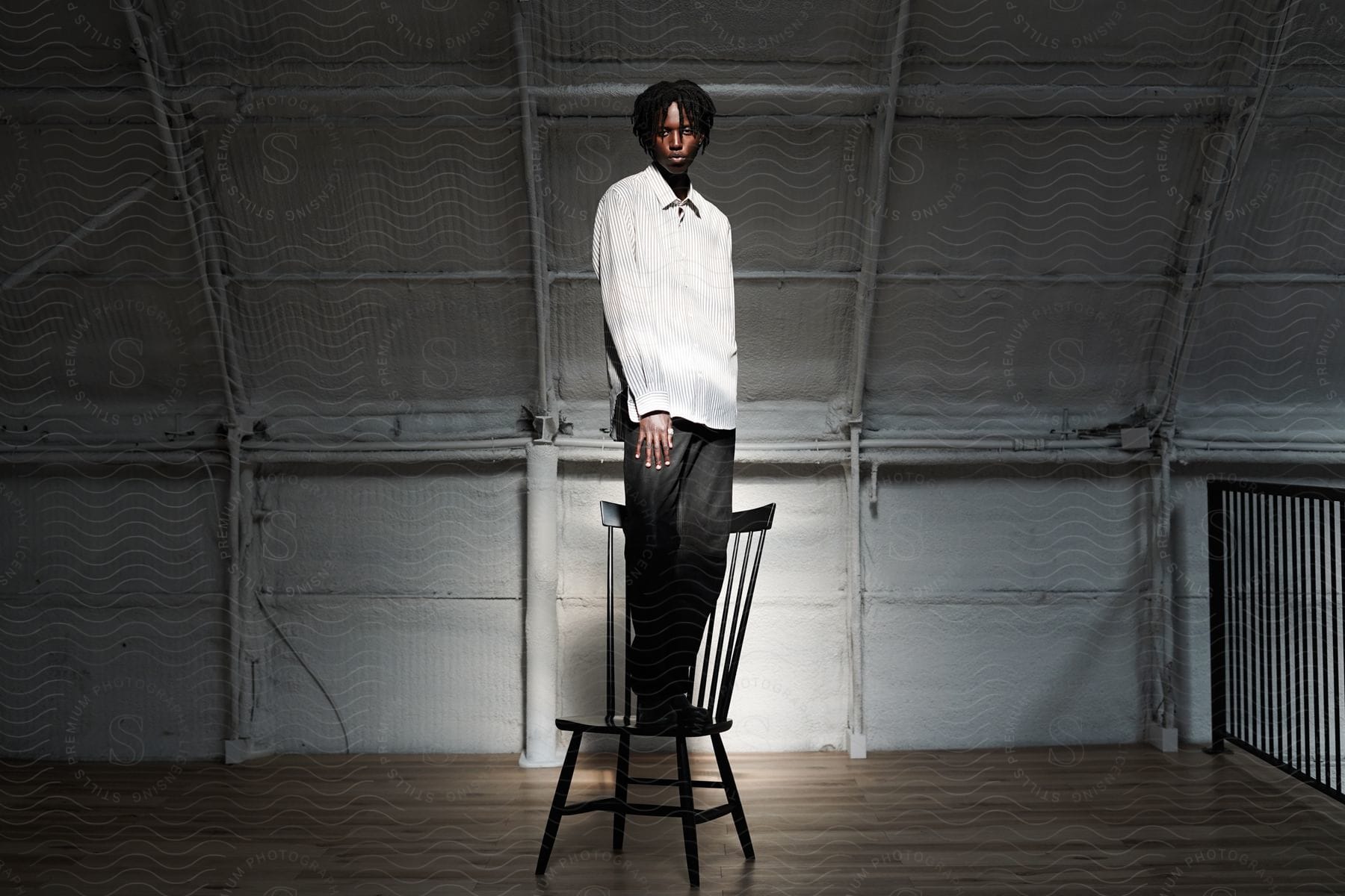 Man standing on a chair wearing pants and a formal shirt