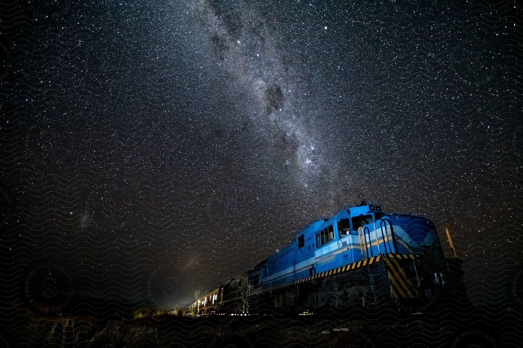 A train travels through the mountains under the stars of the Milky Way